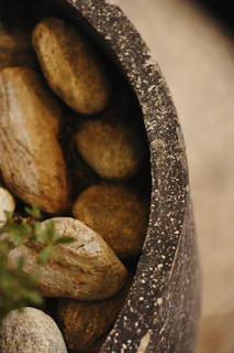 Smooth river stones fill a dark textured pot