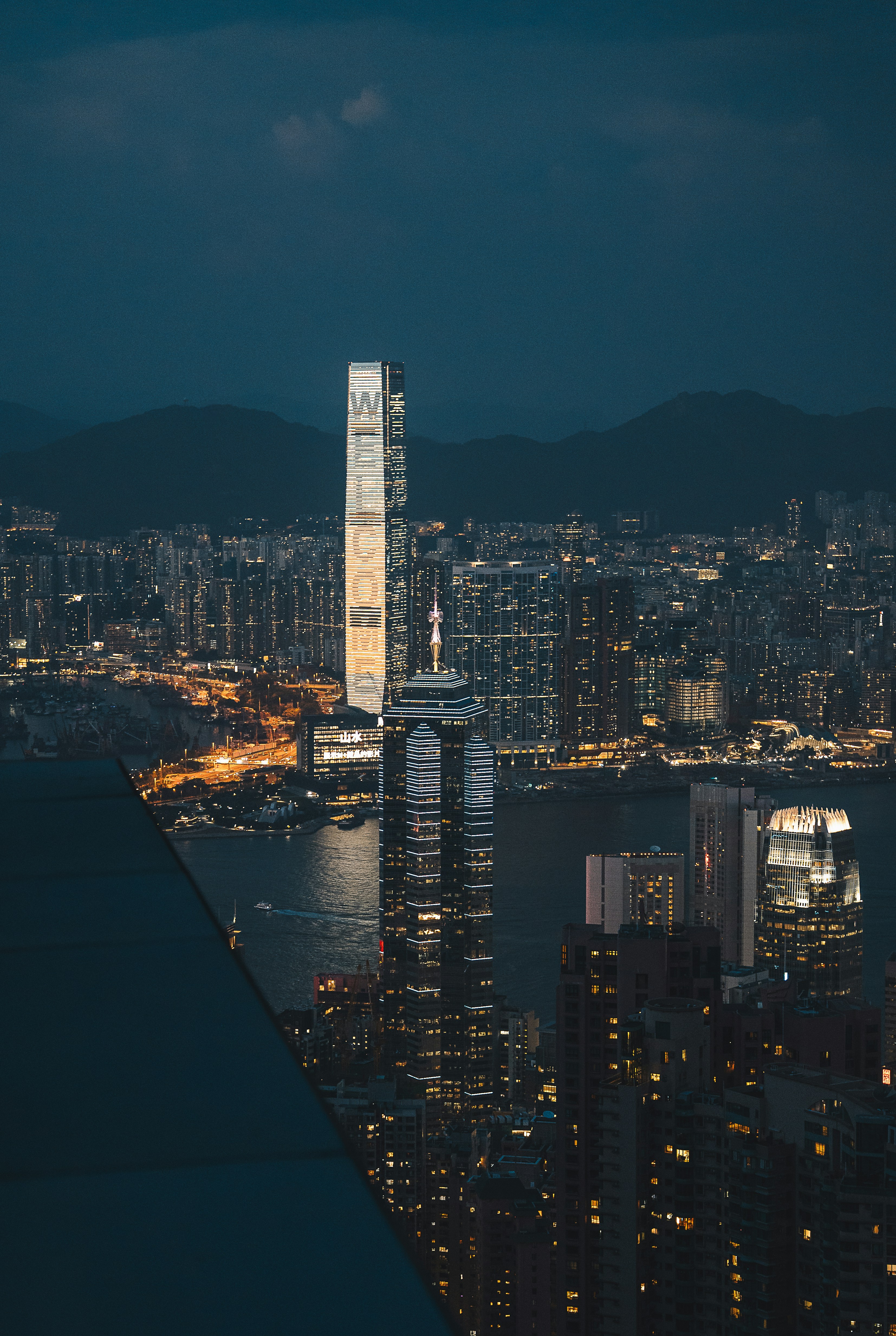 Modern skyscrapers illuminated at night overlooking a bay.