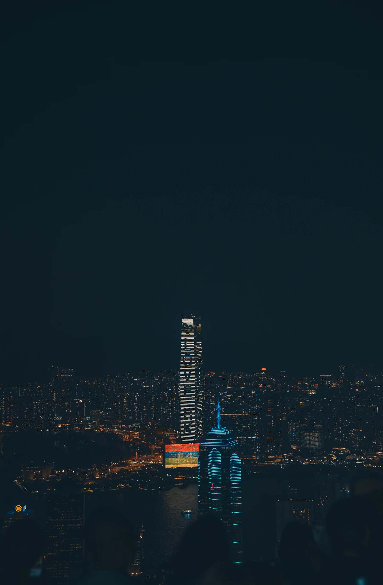 Hong Kong's skyline at night, viewed from a hillside vantage point above the harbour