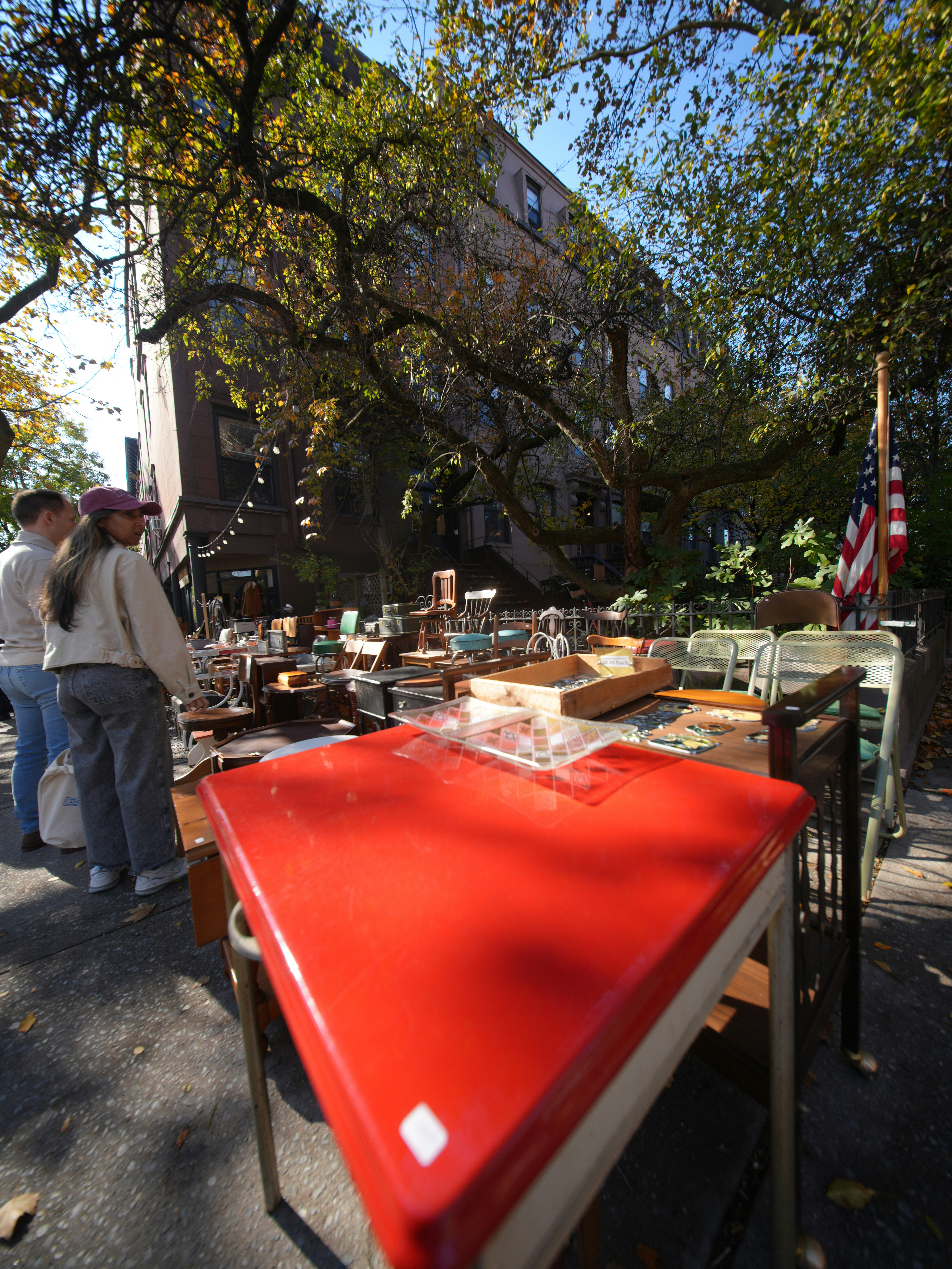 Outdoor flea market with tables of assorted goods.