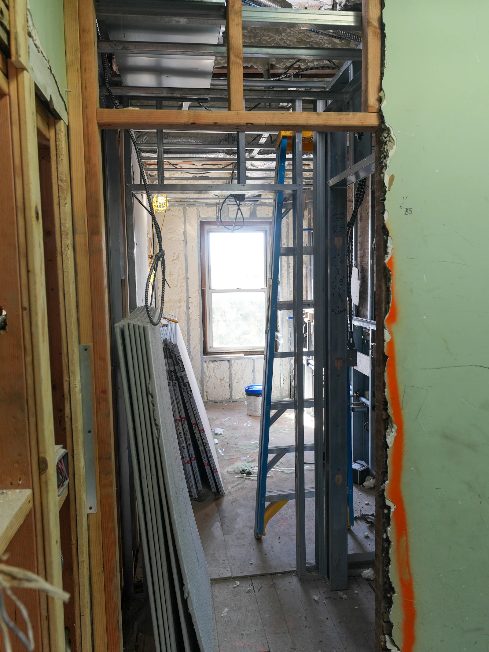 Interior framing with stacked drywall and a ladder