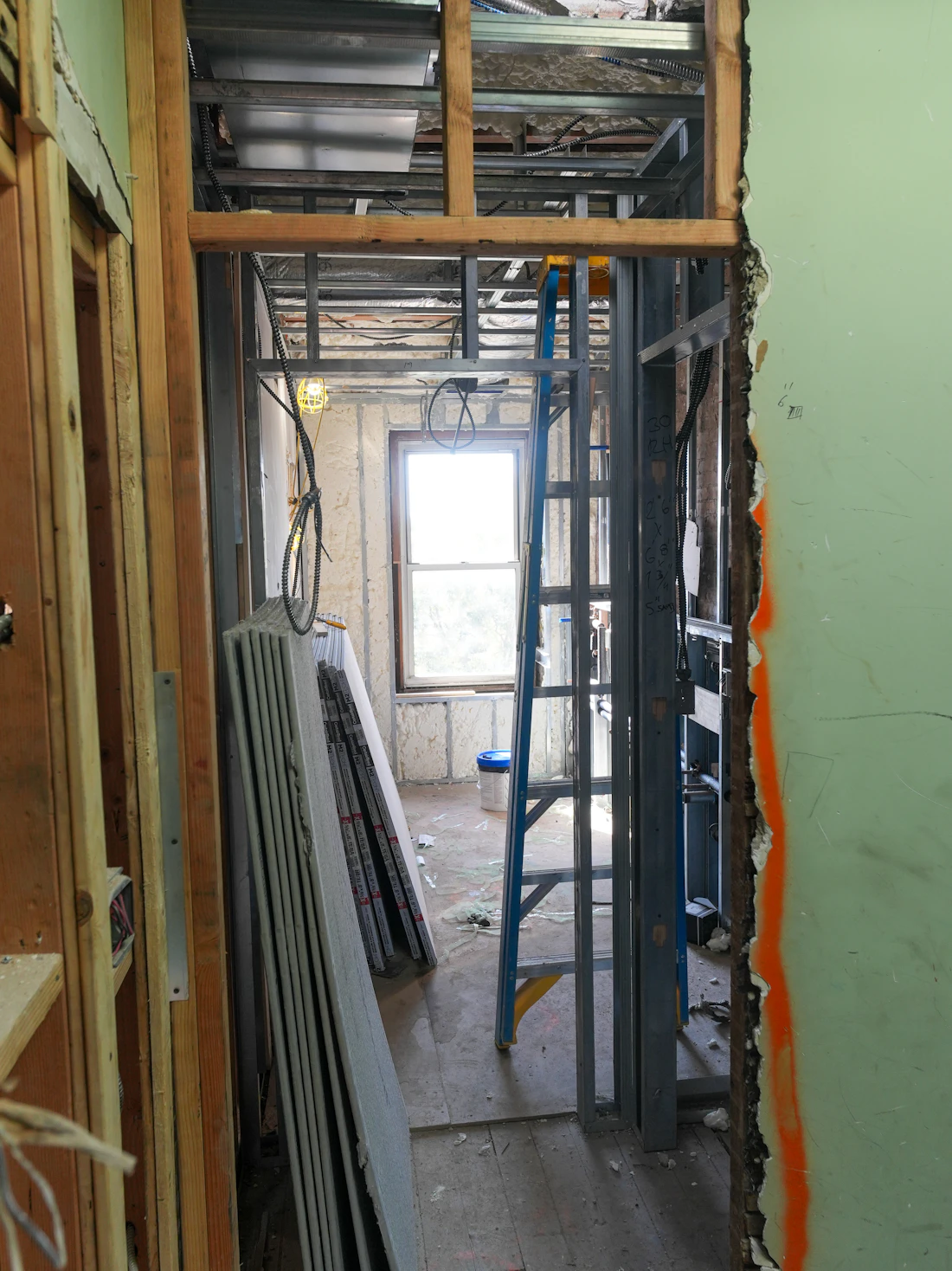 Interior framing with drywall sheets and a ladder during a renovation