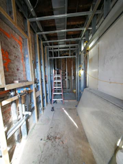 Hallway under construction with metal studs and ladder.