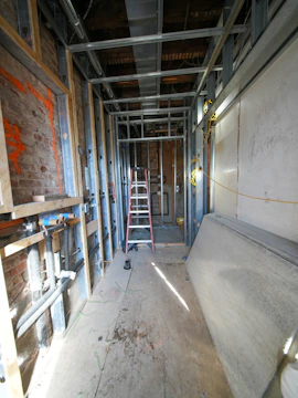 Hallway under construction with metal studs and ladder.