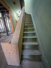 Wooden staircase under construction with green walls