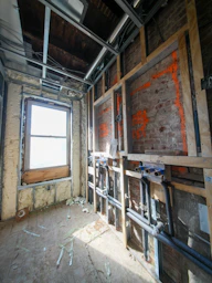 Interior under construction with exposed pipes and window