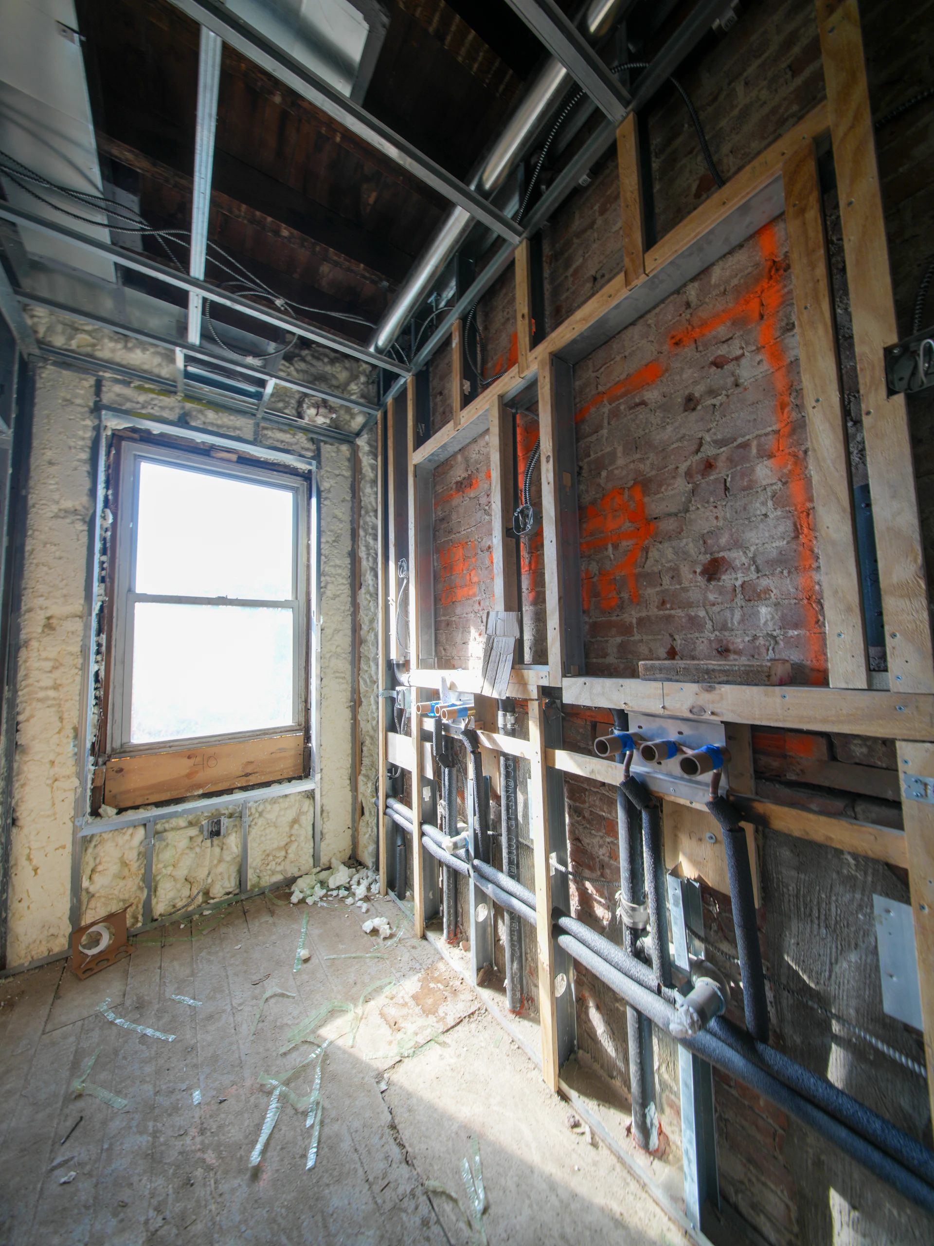 Interior under construction with exposed pipes and window