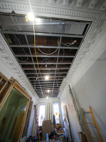 Interior hallway under renovation with exposed ceiling and wiring.