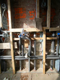 Plumbing pipes being installed in a brick wall.