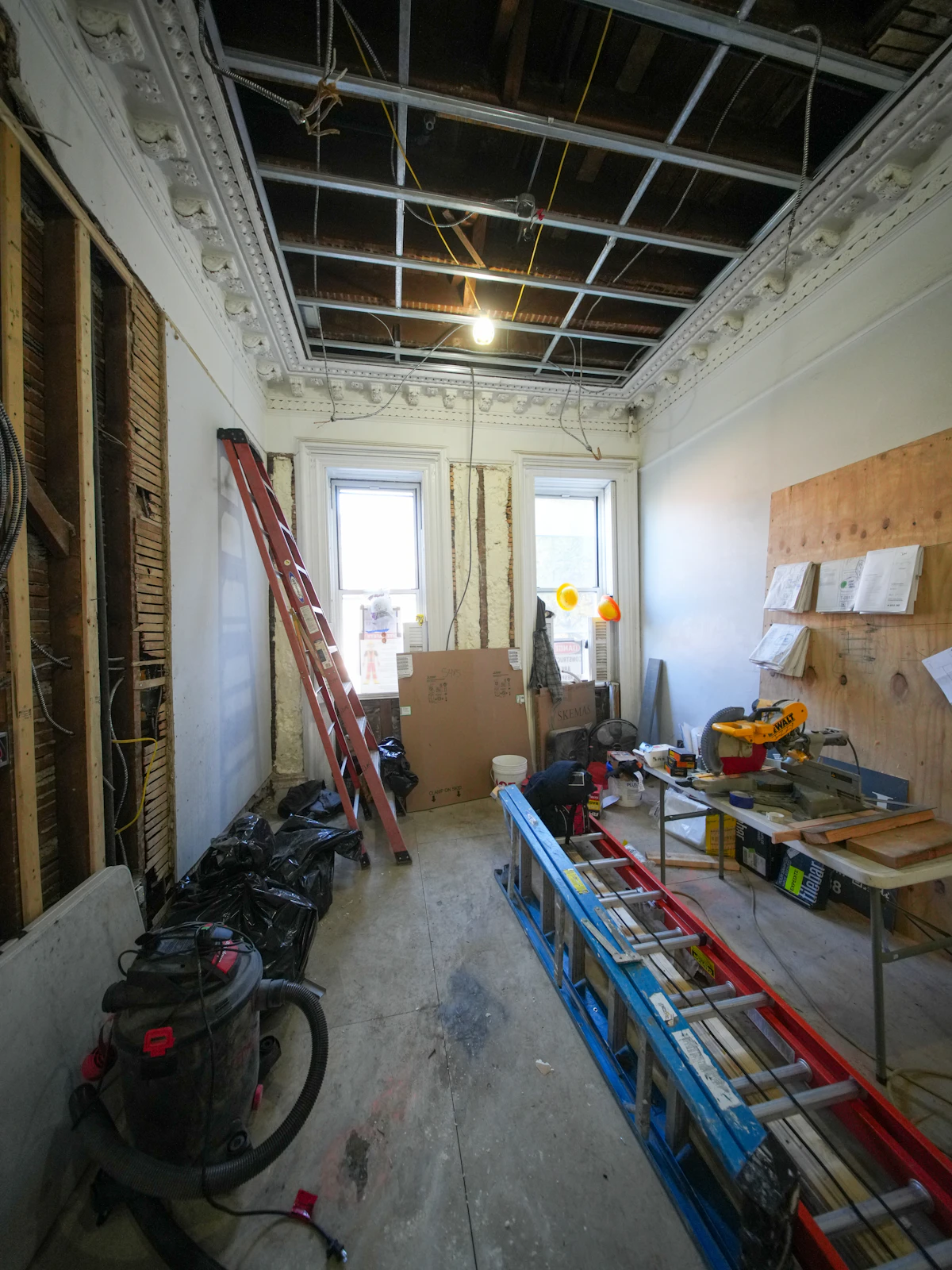 A gutted room with tools and a shop vacuum