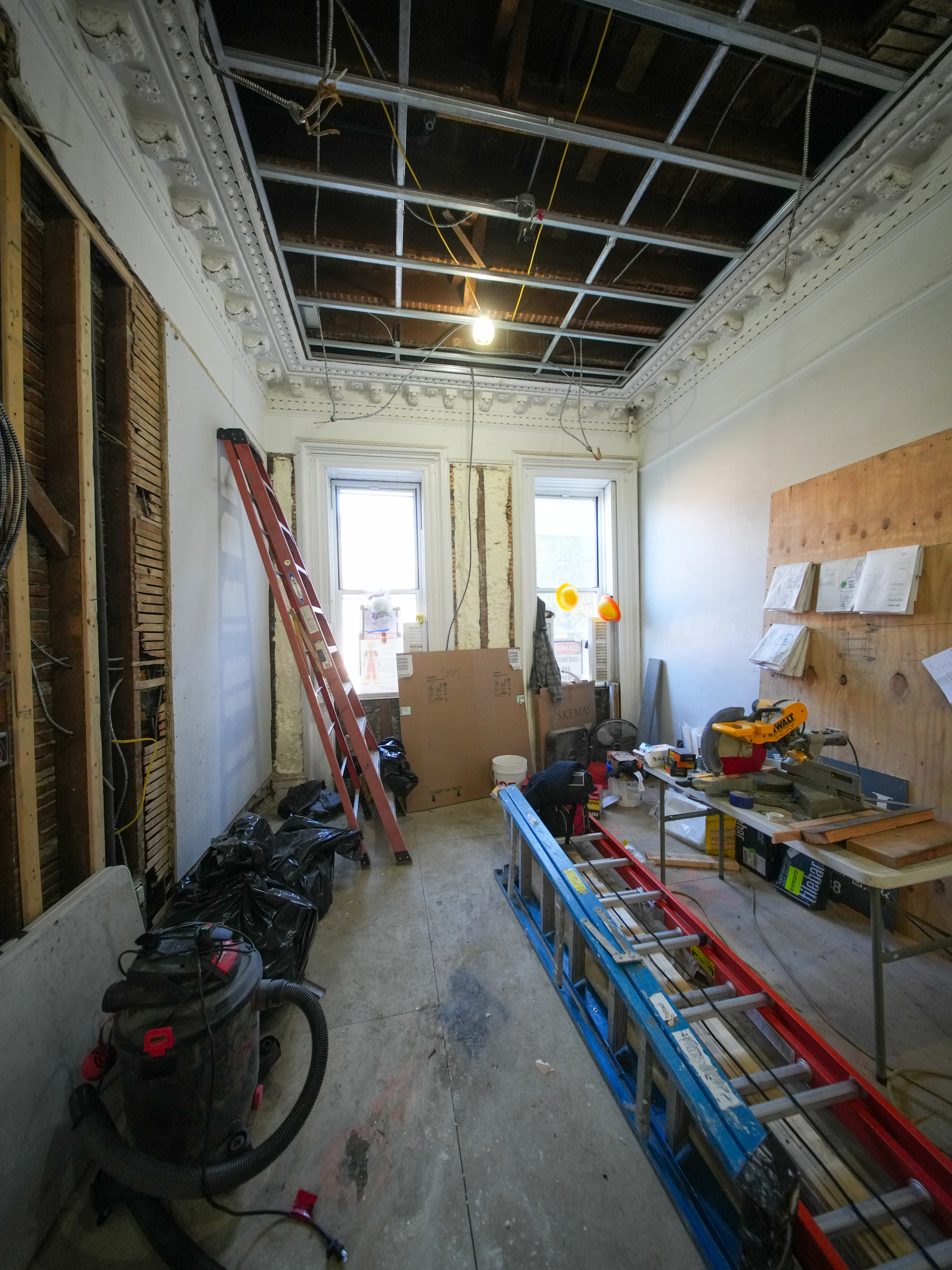 Interior renovation project with exposed ceiling, ladders and professional tools