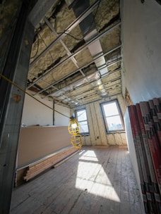 Room under construction with exposed ceiling and drywall sheets.