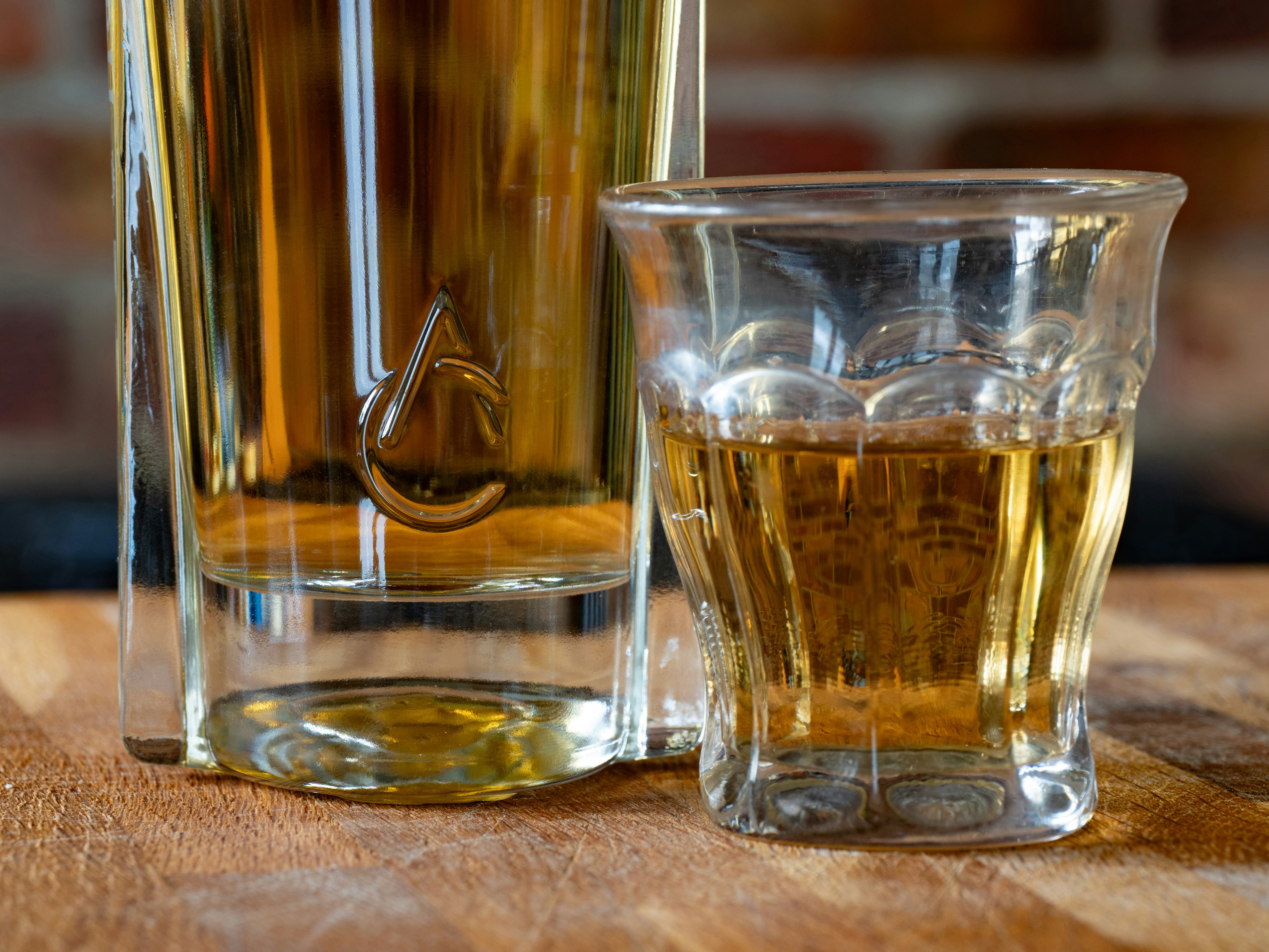 Two glasses with amber liquid on wooden surface.