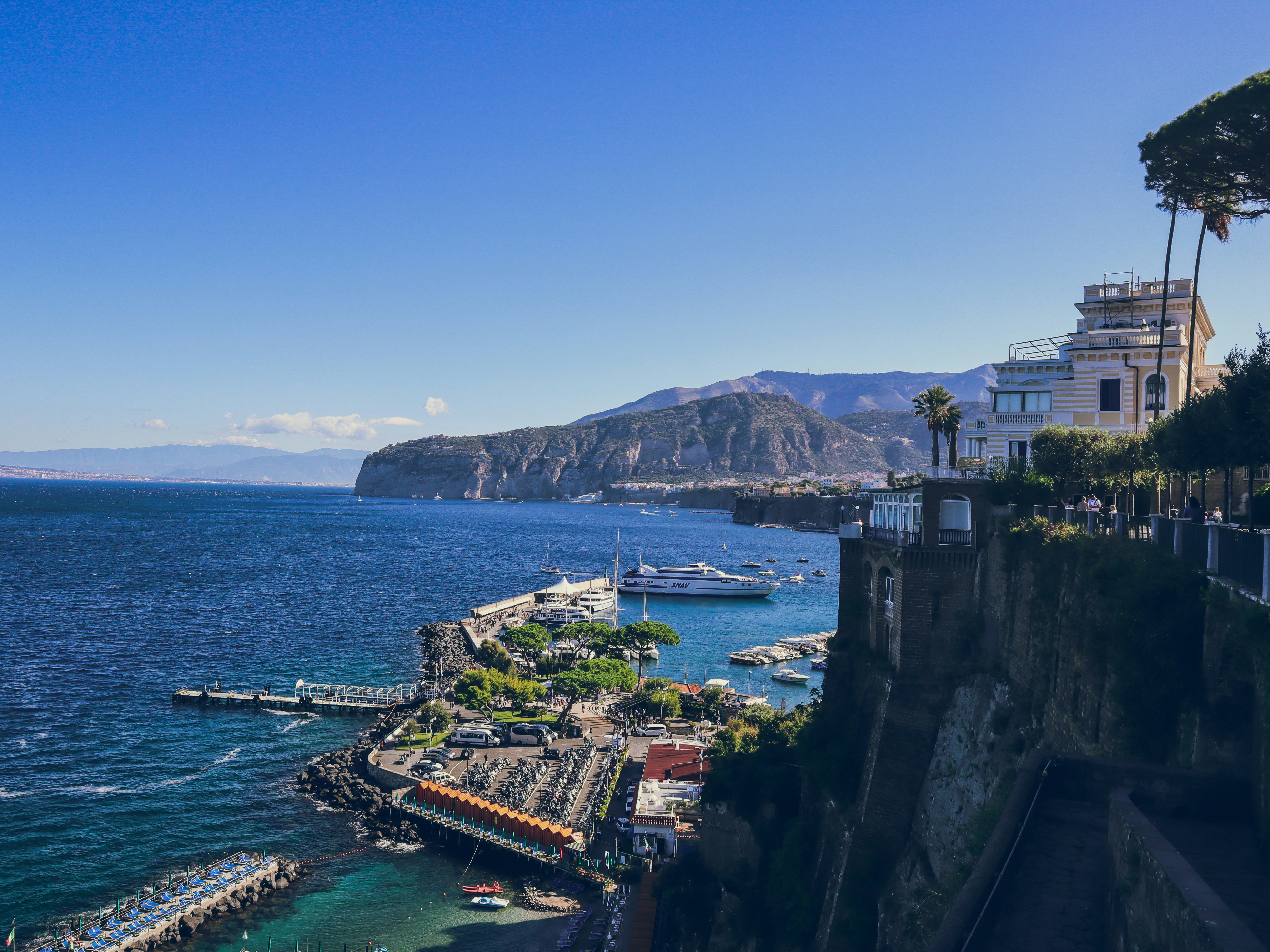 Sorrento harbour coastline with docks and boats along a rocky waterfront, with a large white yacht
