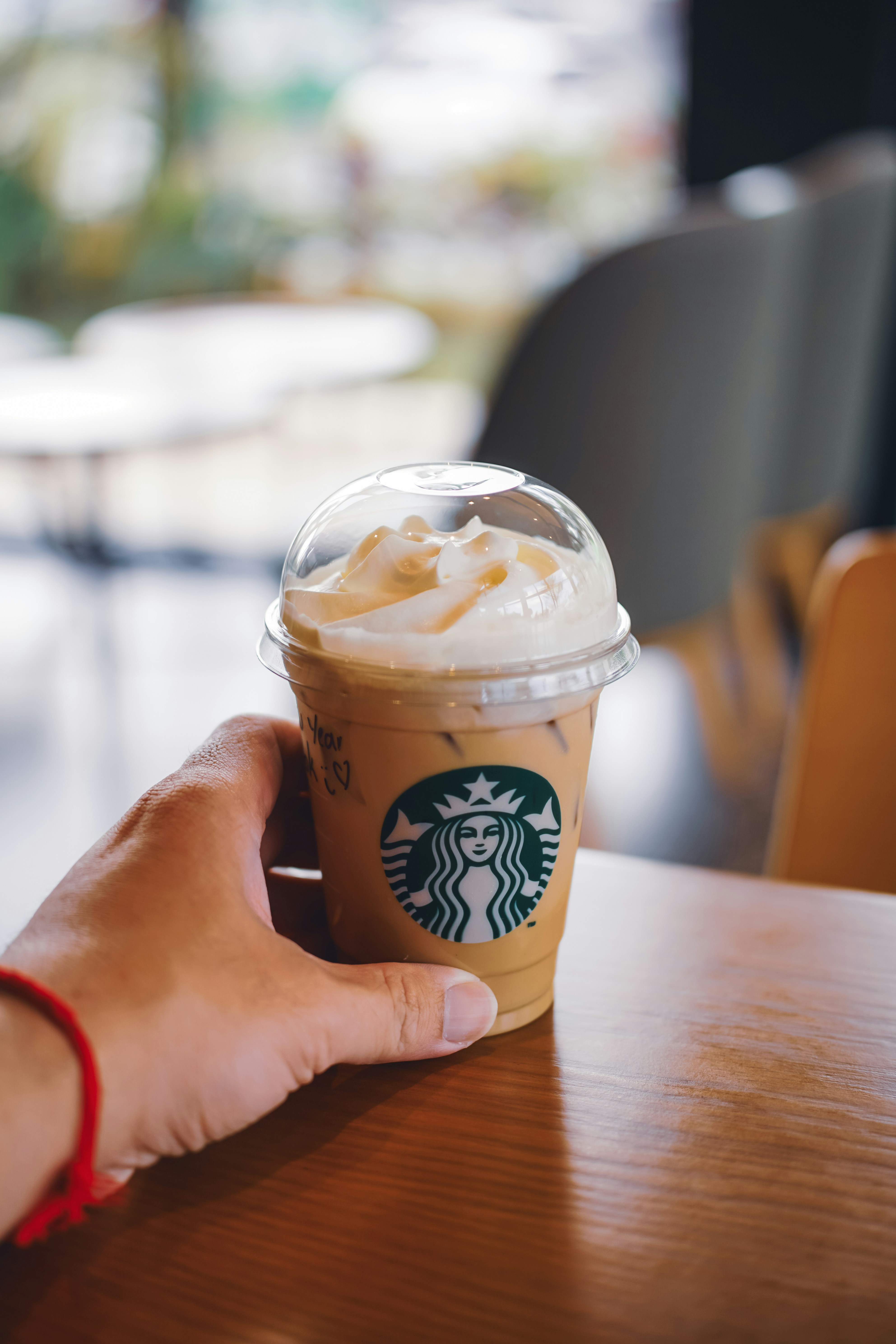 Main tenant un café glacé Starbucks avec de la crème fouettée
