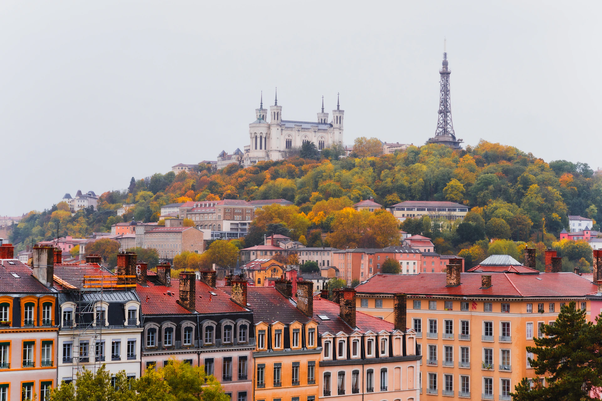 Autumn cityscape with buildings and a tower on a hill