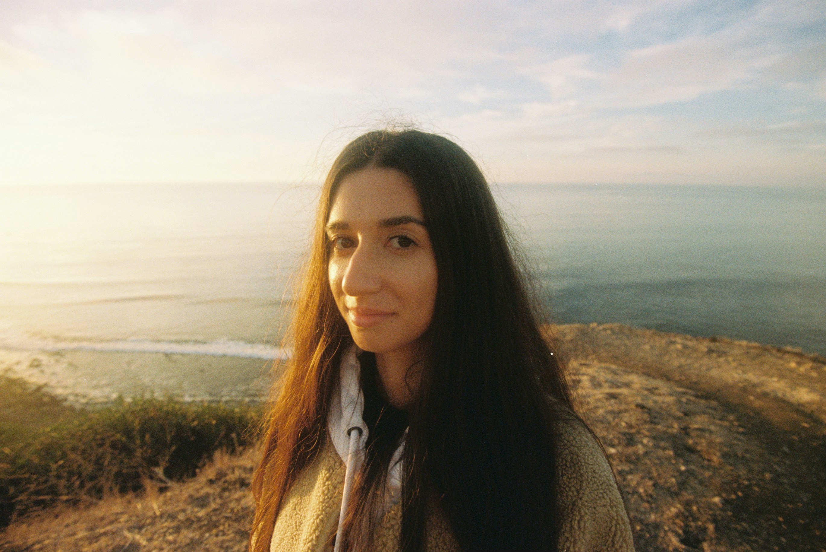 Giovane donna con lunghi capelli scuri vicino all'oceano