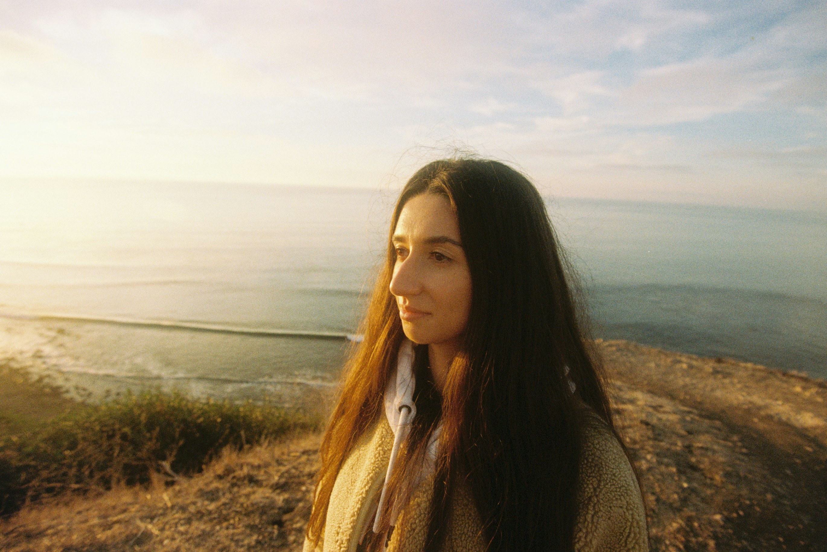Joven en un acantilado con vistas al mar al atardecer