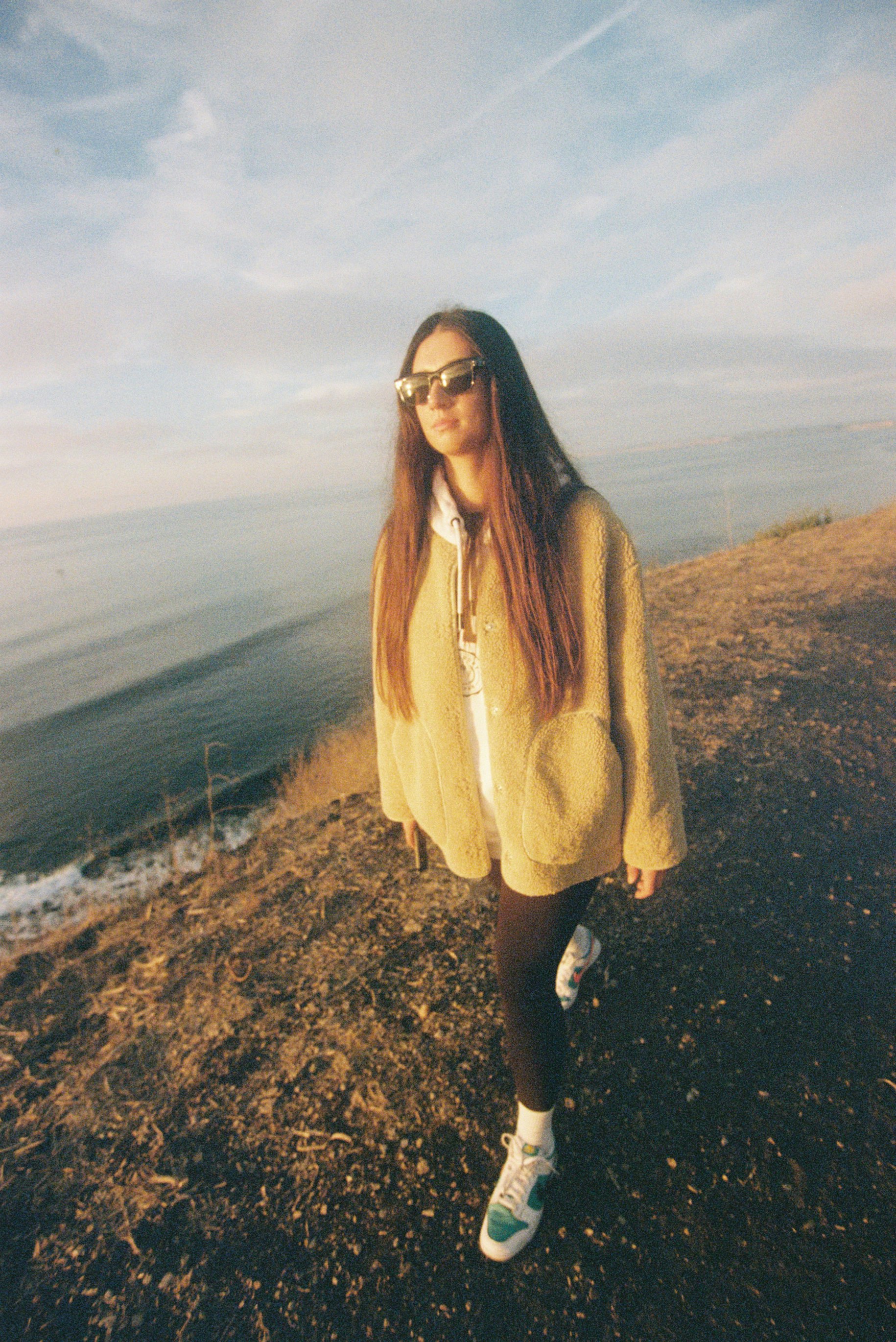 Giovane donna che cammina su un sentiero costiero al tramonto