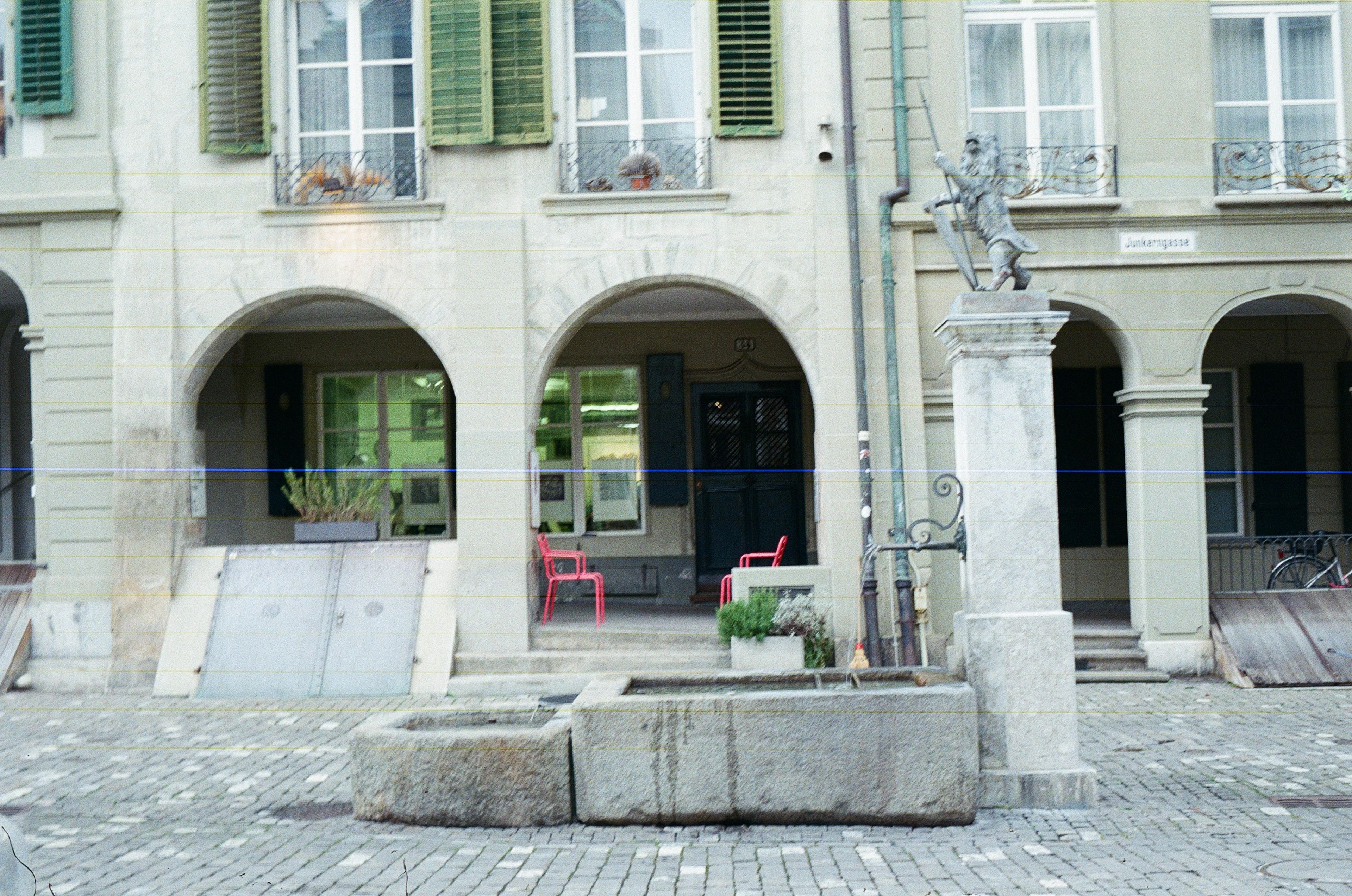 A stone fountain in front of an arched building, like those on Bern’s Bundesplatz