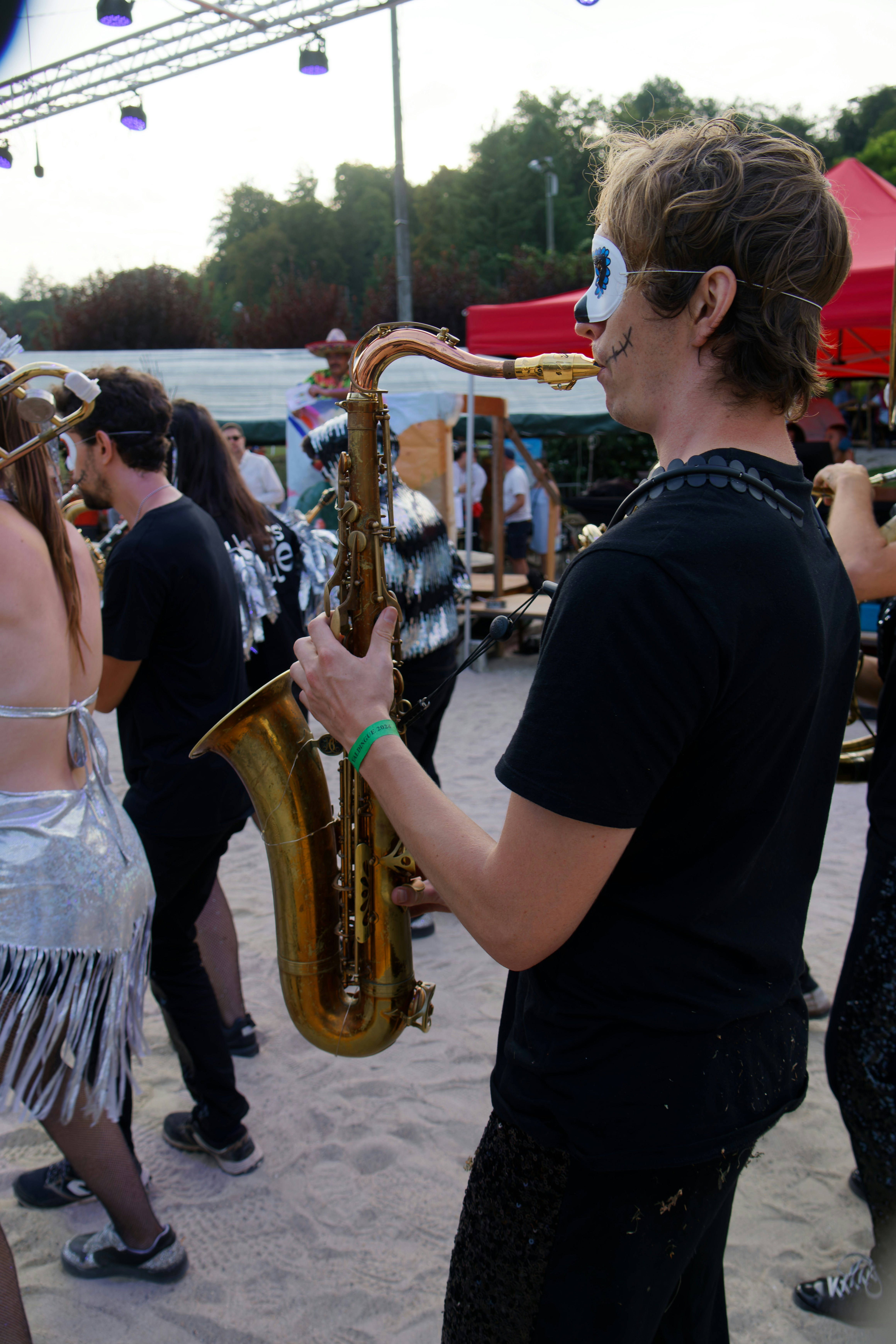 Man in skull makeup plays saxophone at outdoor event