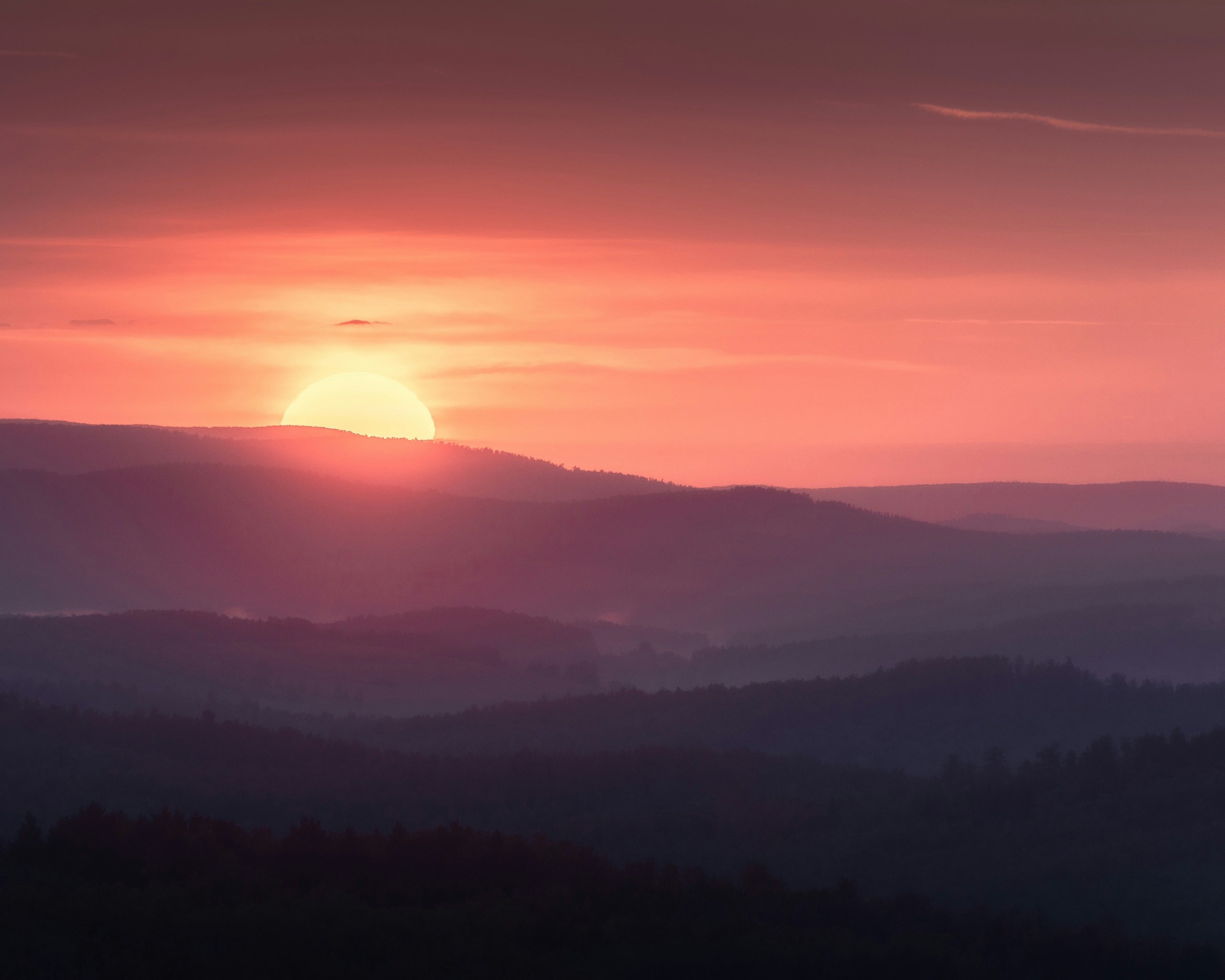 Nascer do sol sobre cadeias de montanhas em camadas com céu rosa