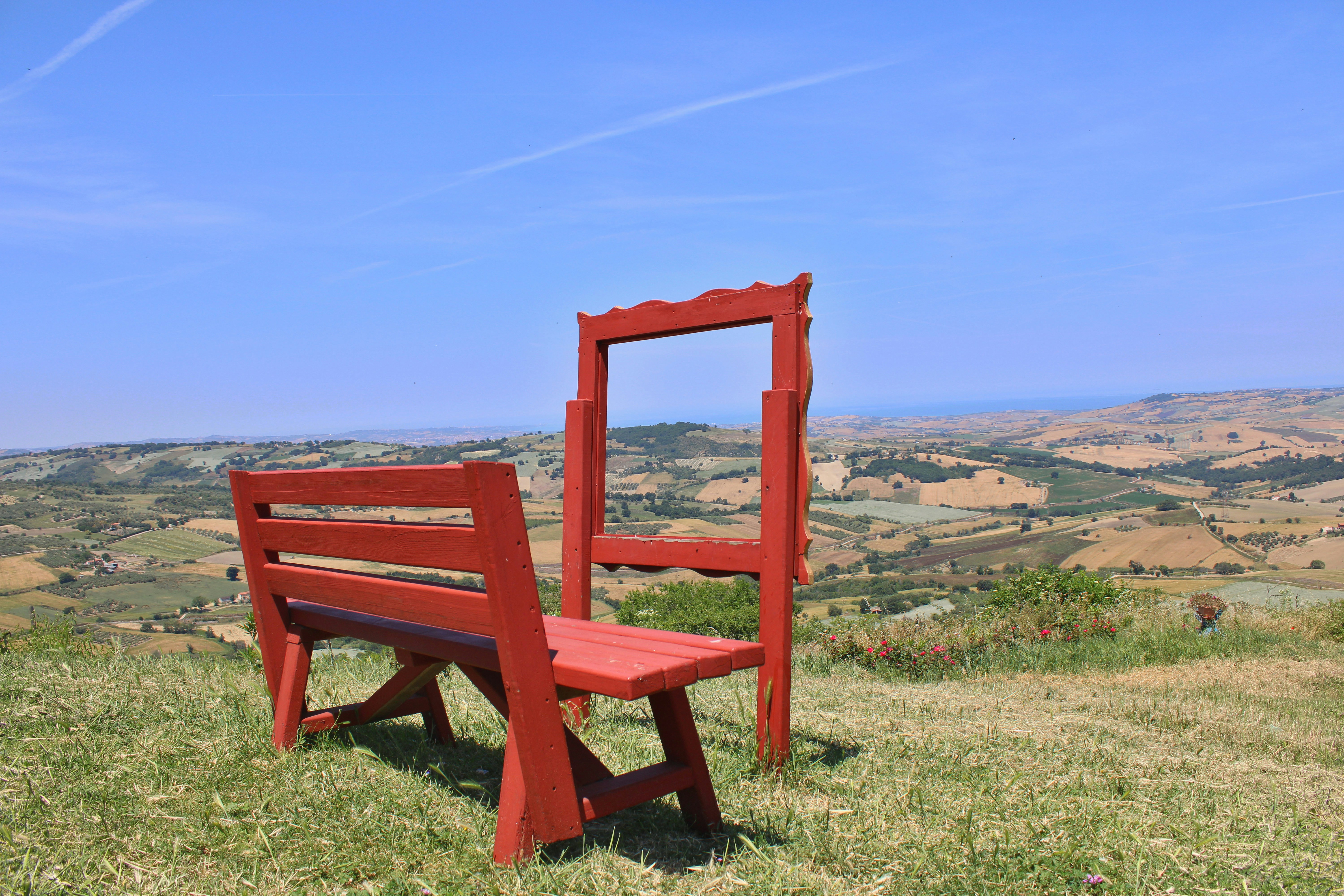 A bright red bench overlooks a rolling landscape.