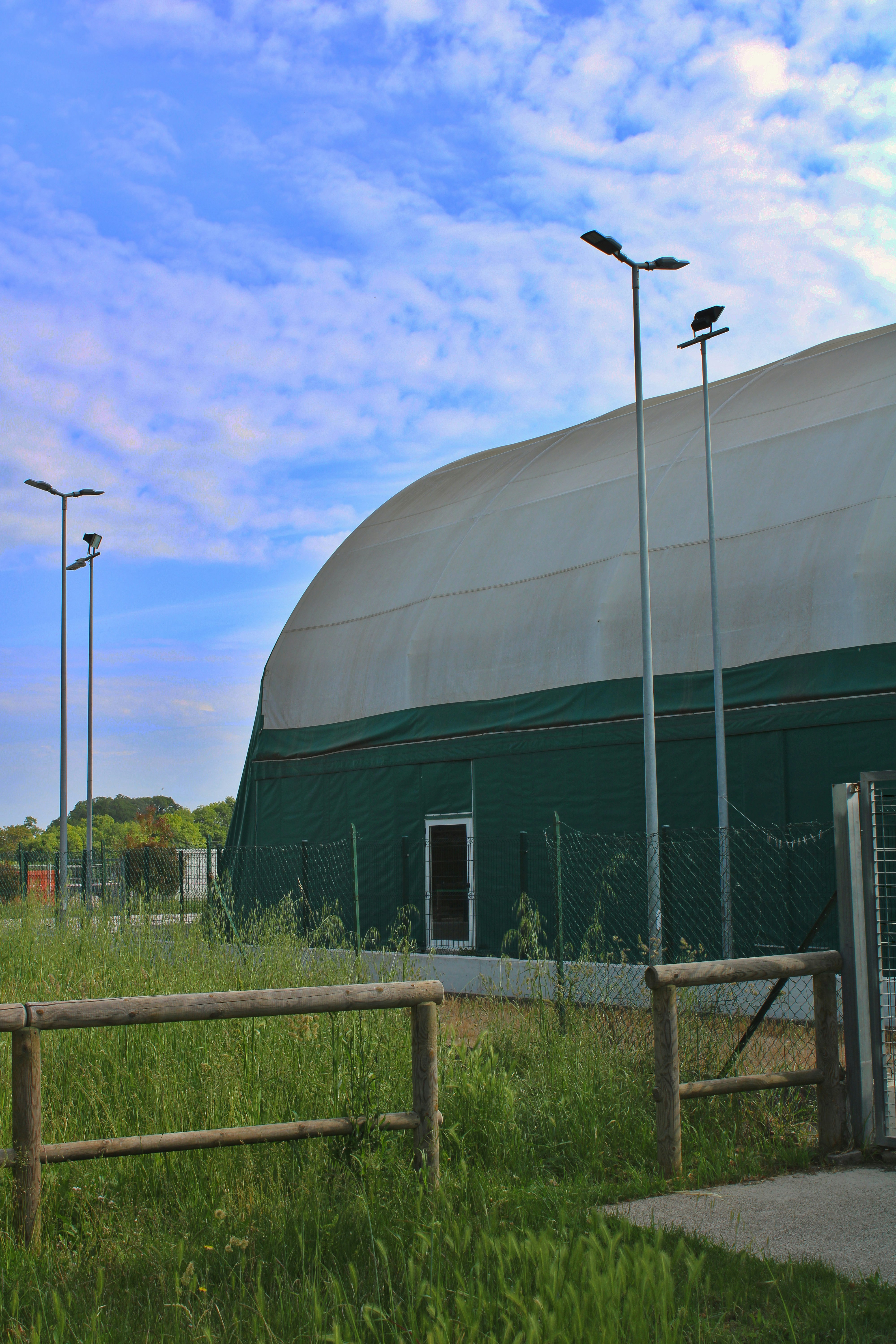 Large white and green sports dome under a blue sky.