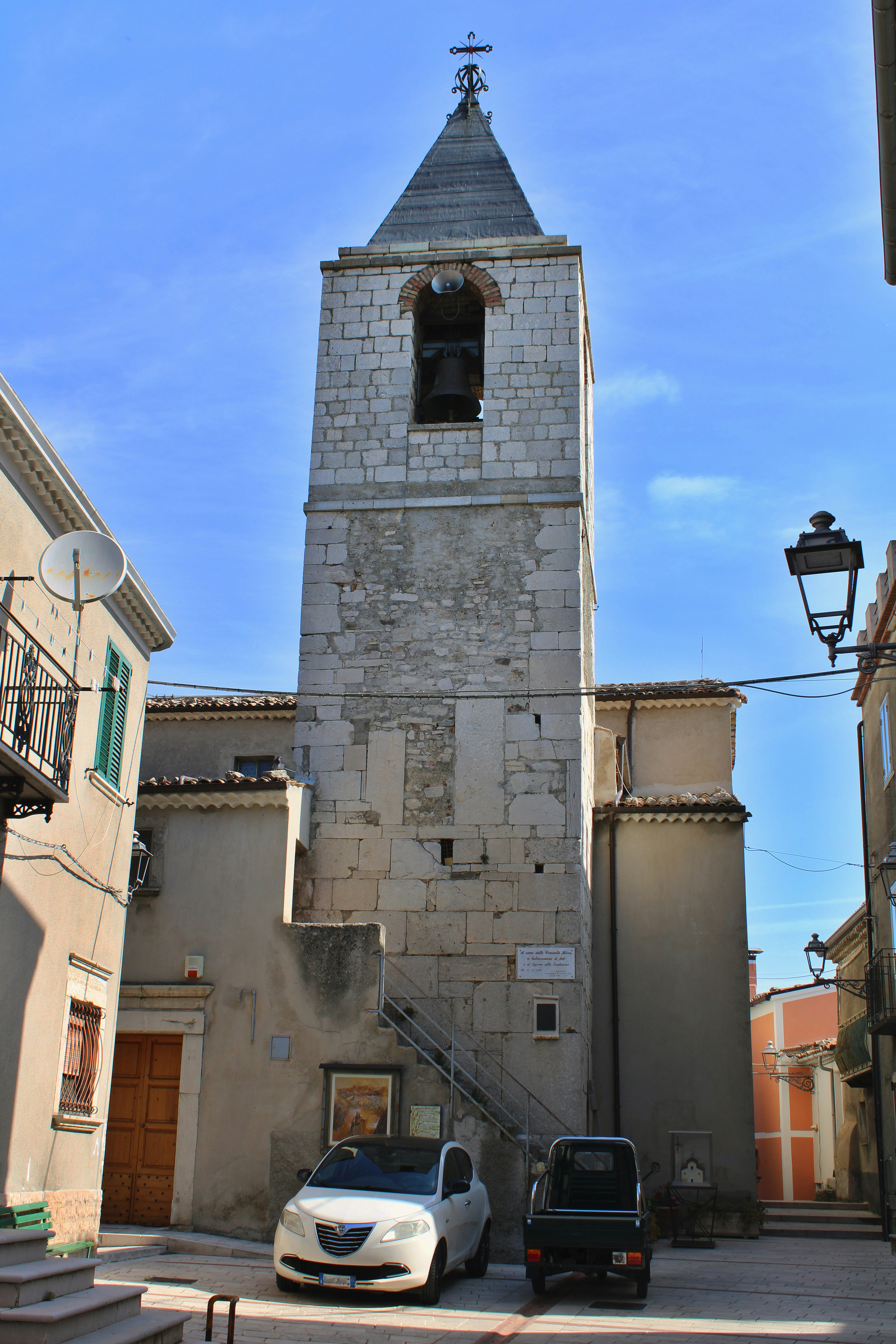 Stone bell tower with a bell and a cross