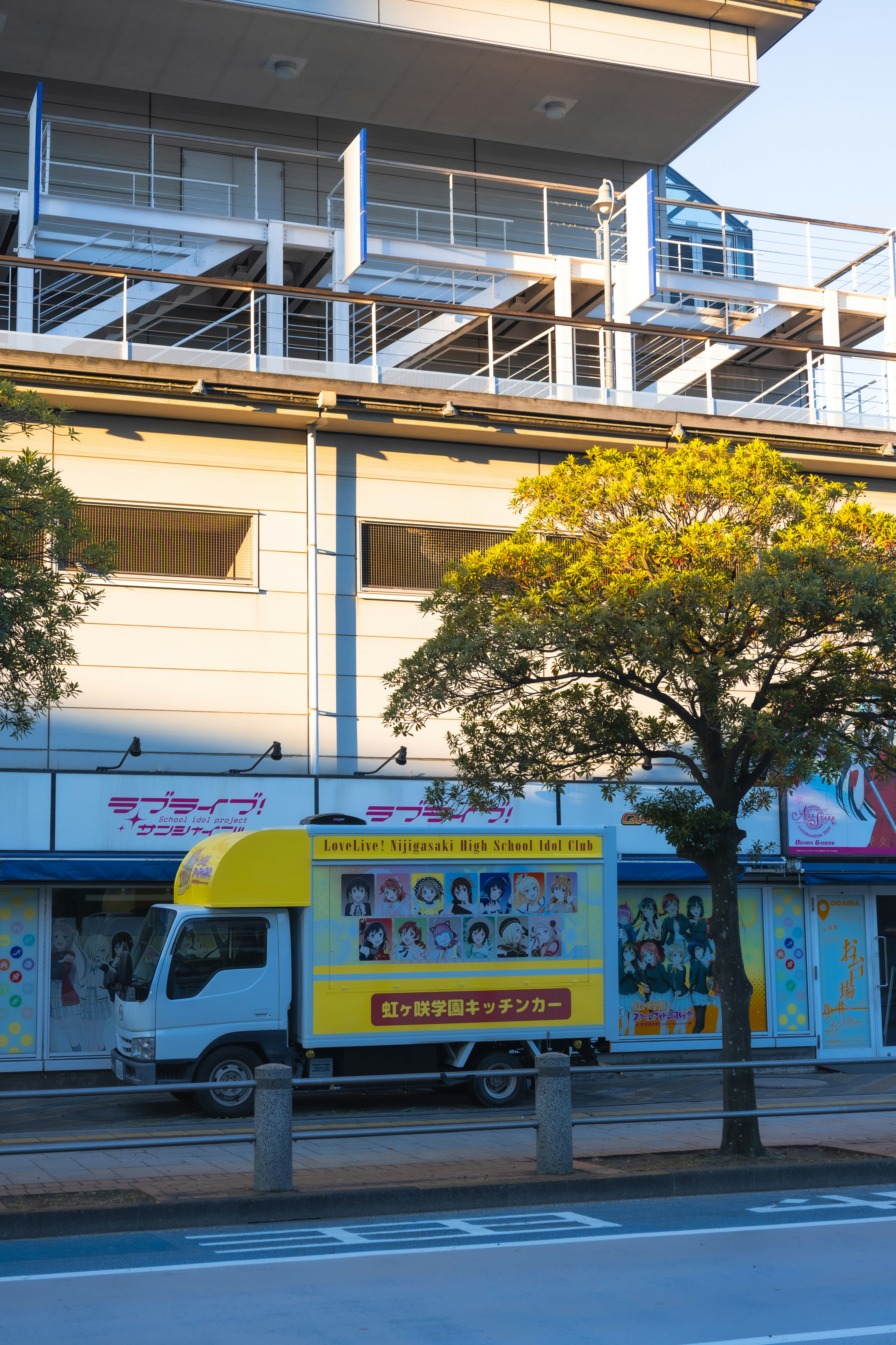 A yellow truck with anime characters parked outside a building
