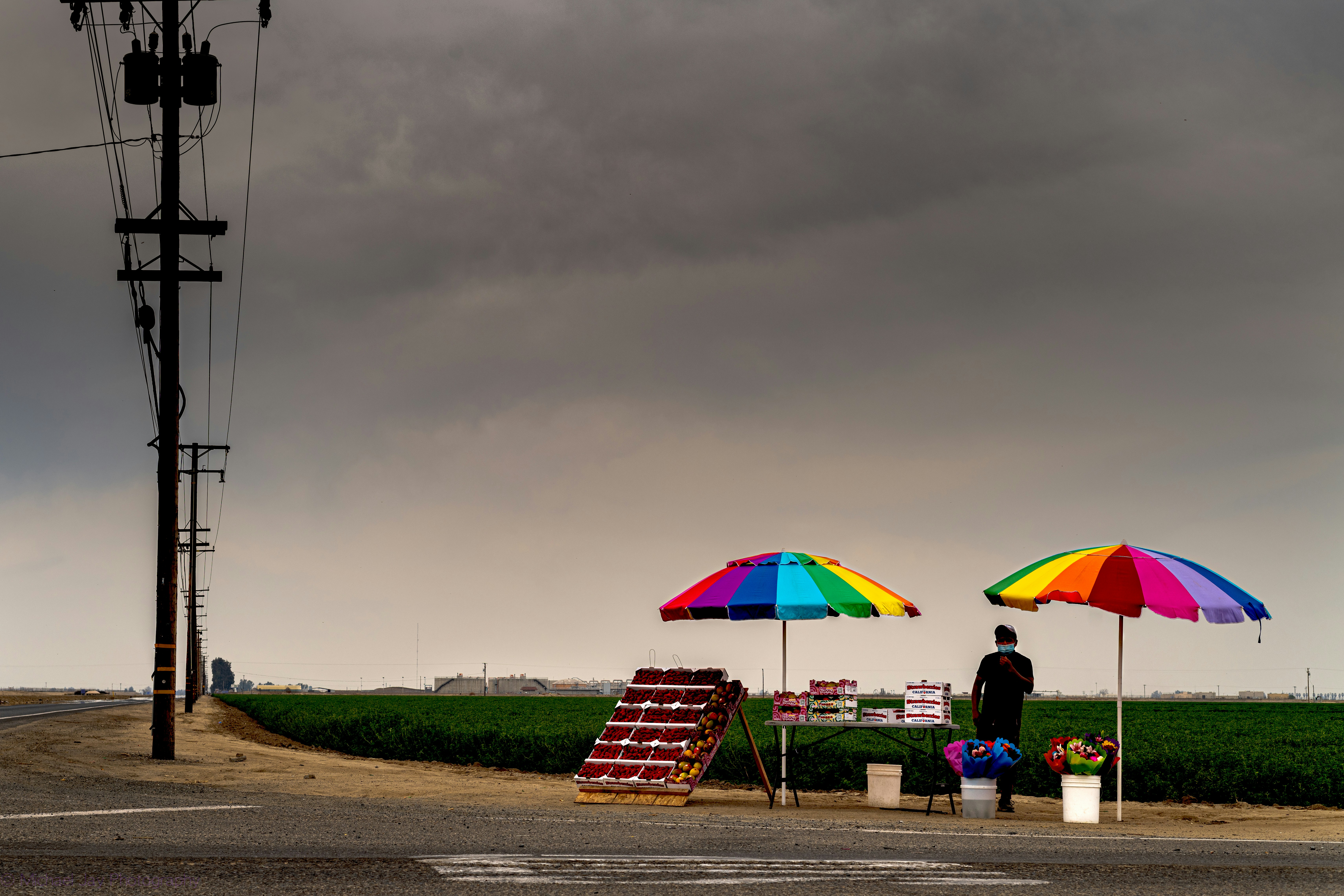 カラフルな傘や野菜を並べたロードサイドスタンド。
