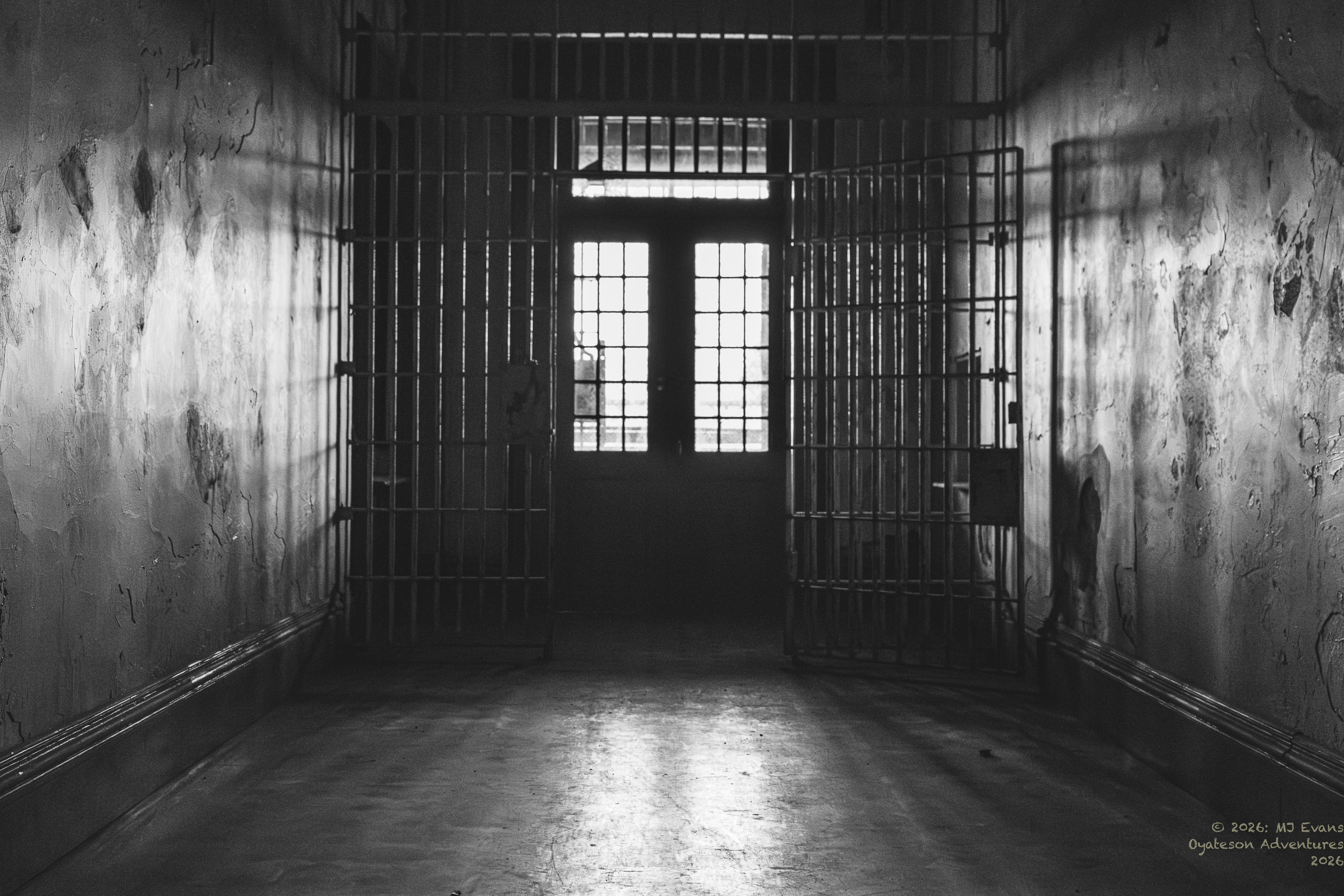 暗く空っぽの刑務所の廊下で、独房の扉は開いている。