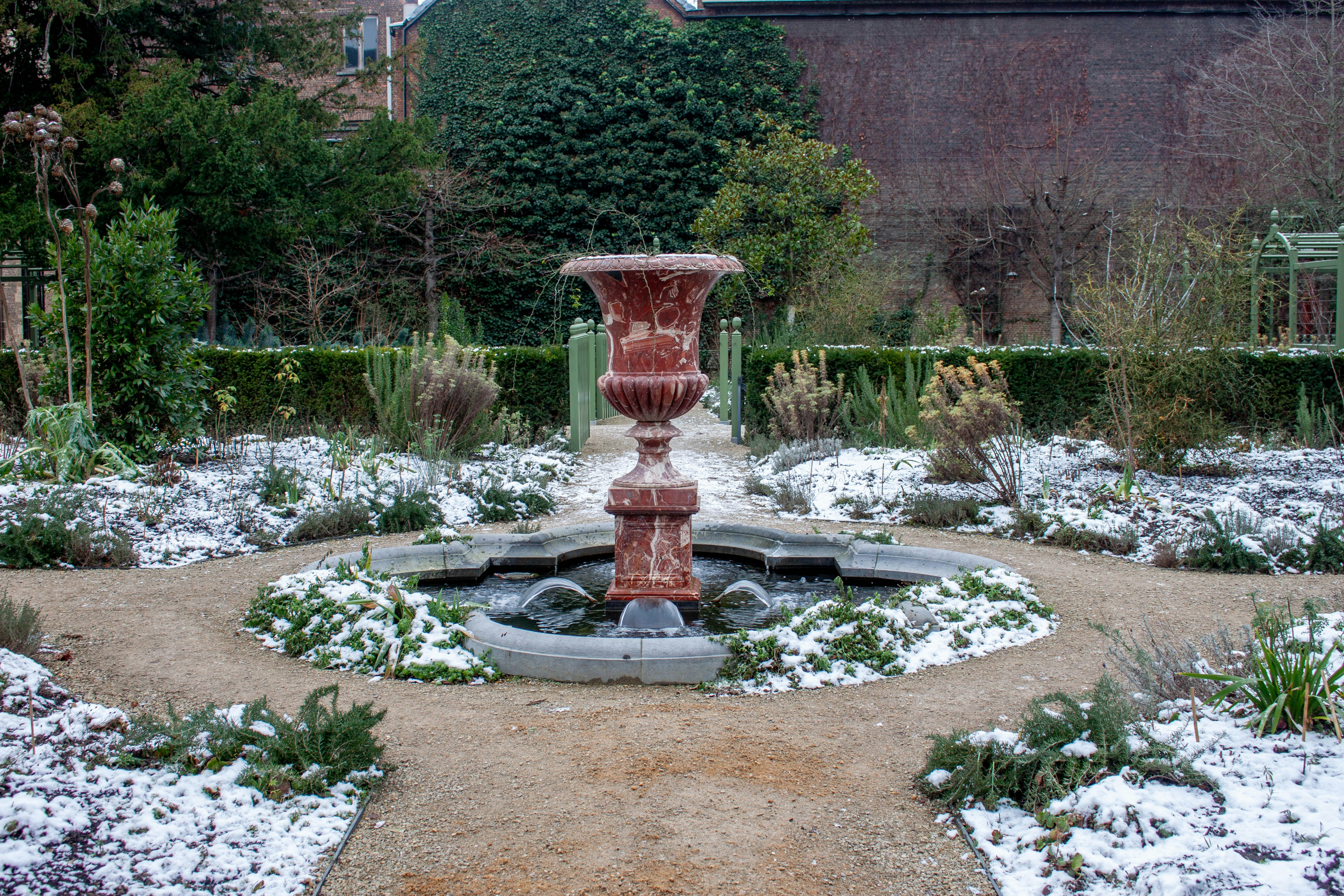 A weathered fountain in a snowy garden