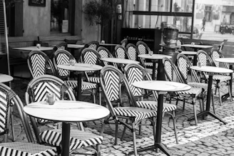 Empty outdoor cafe tables and chairs with patterned upholstery.
