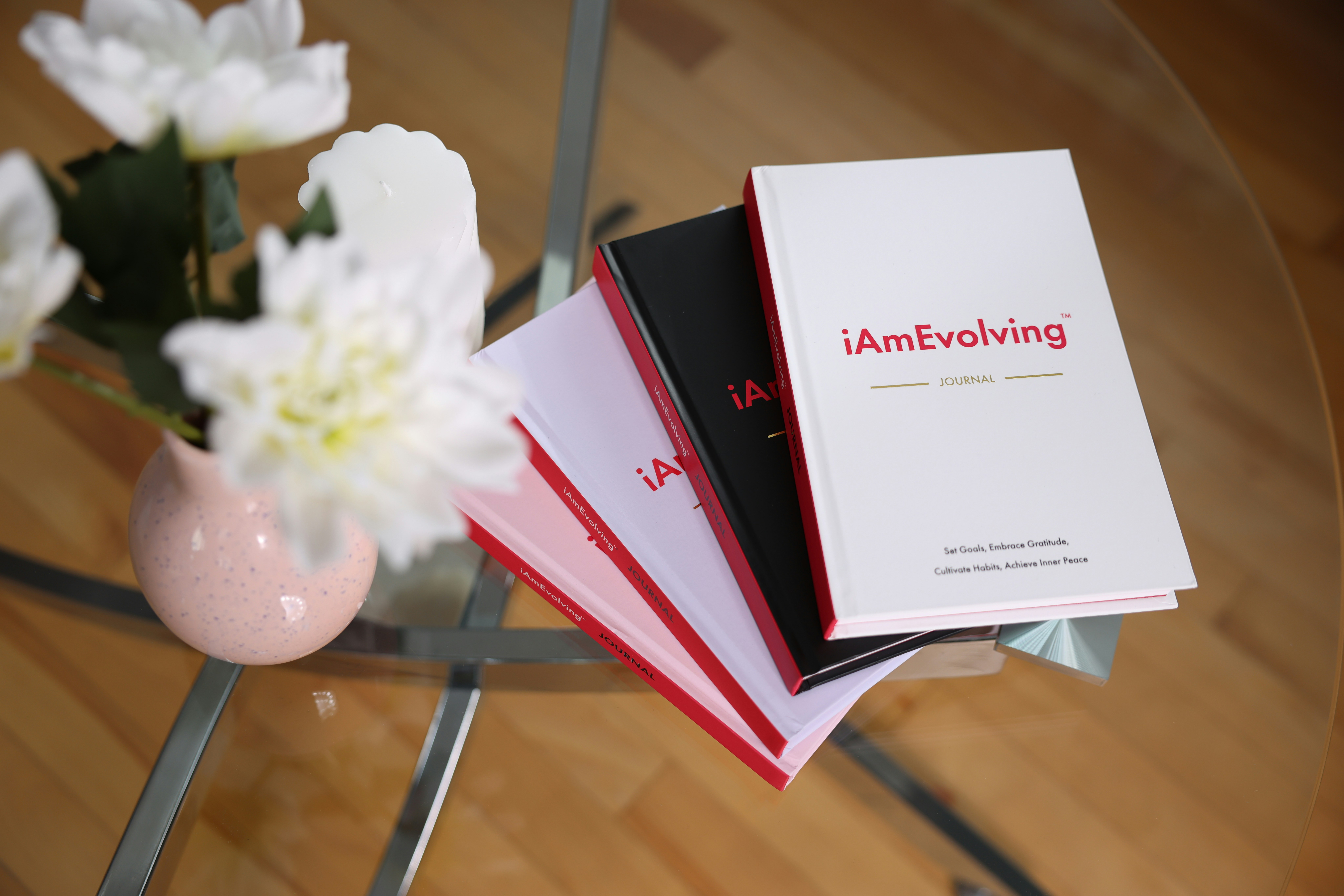 Books stacked on a glass table with flowers.