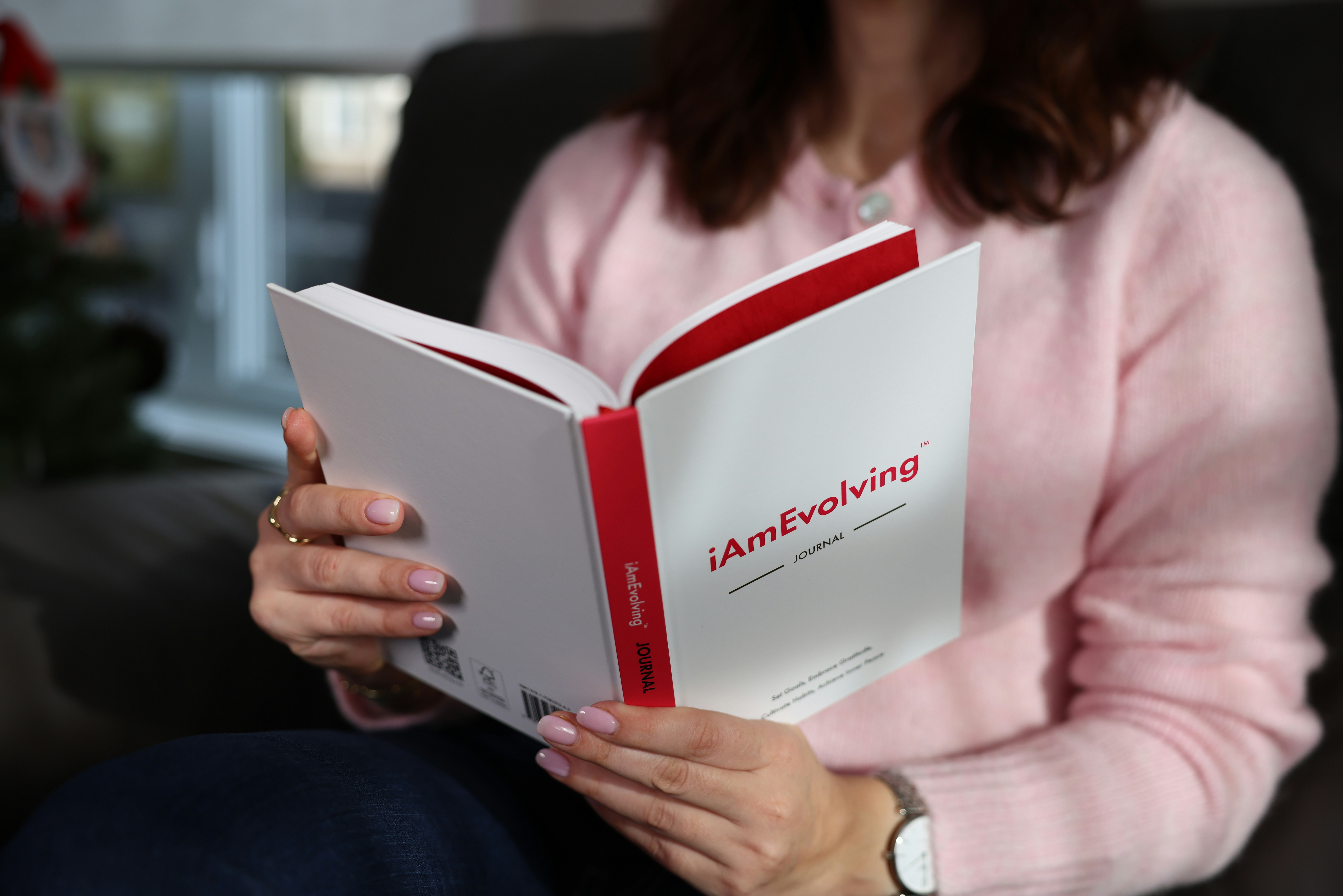 Person in pink sweater reading a white book