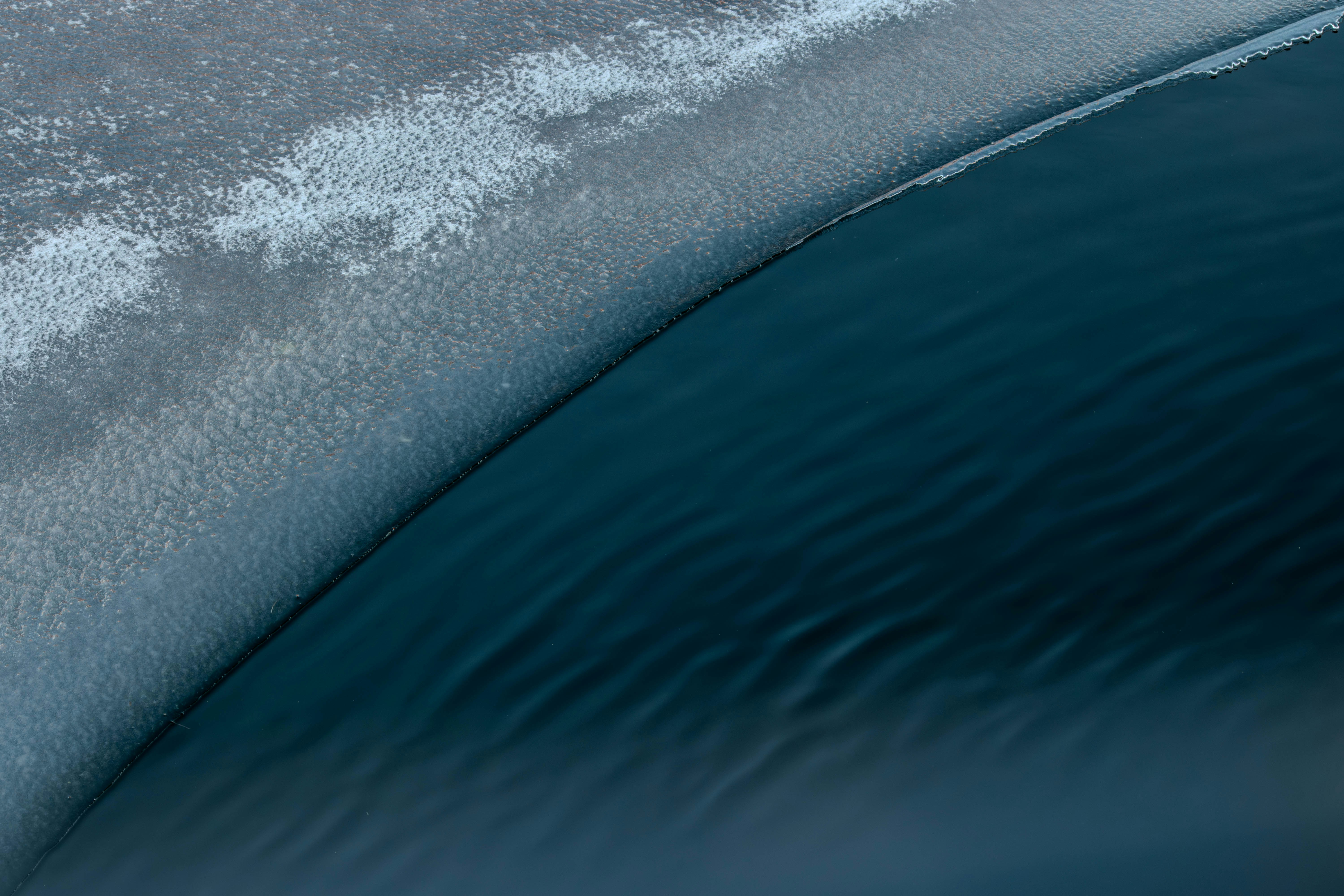 Dunkelblaues Wasser trifft im Winter auf das eisige Ufer