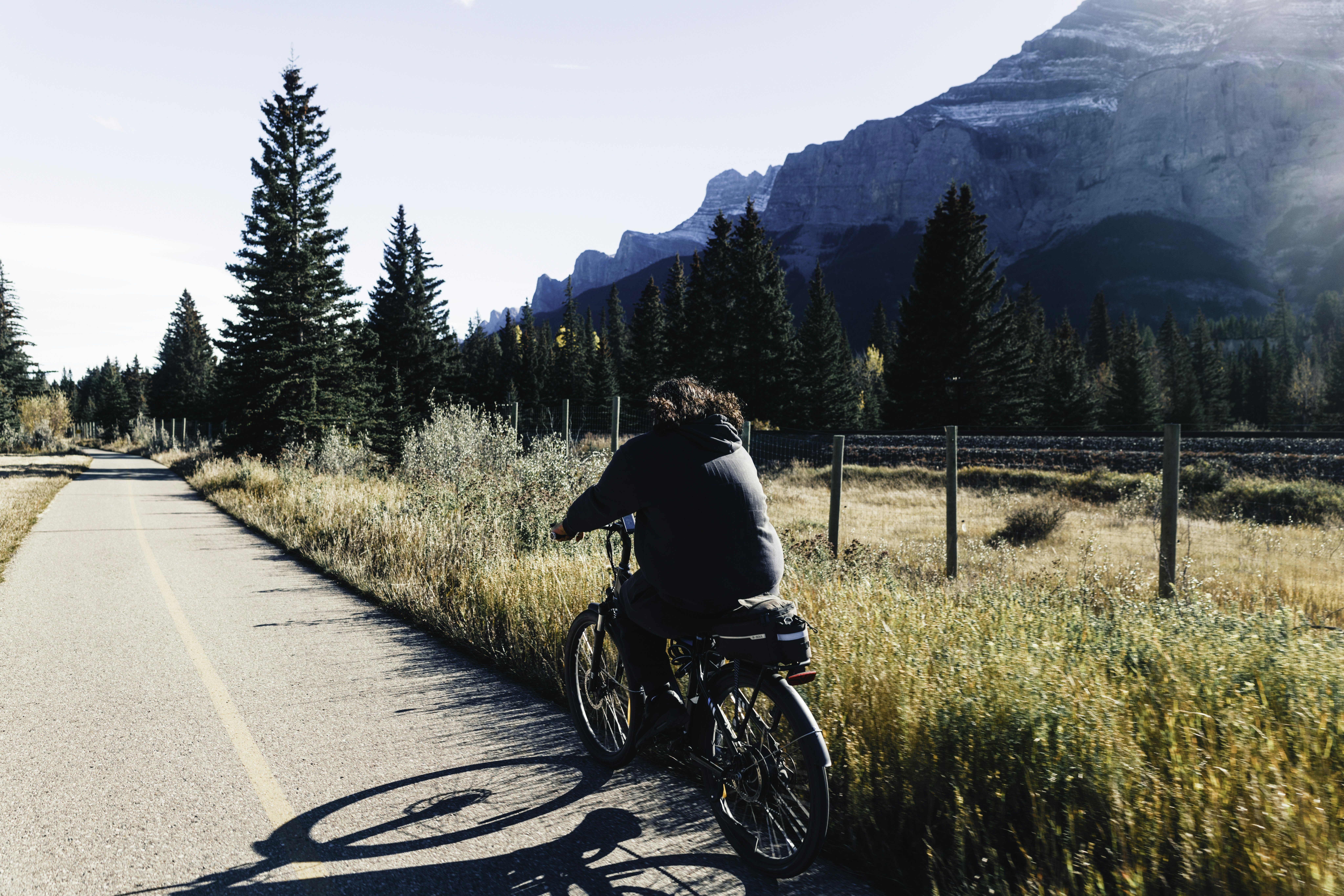 Person riding a bicycle on a path near mountains.