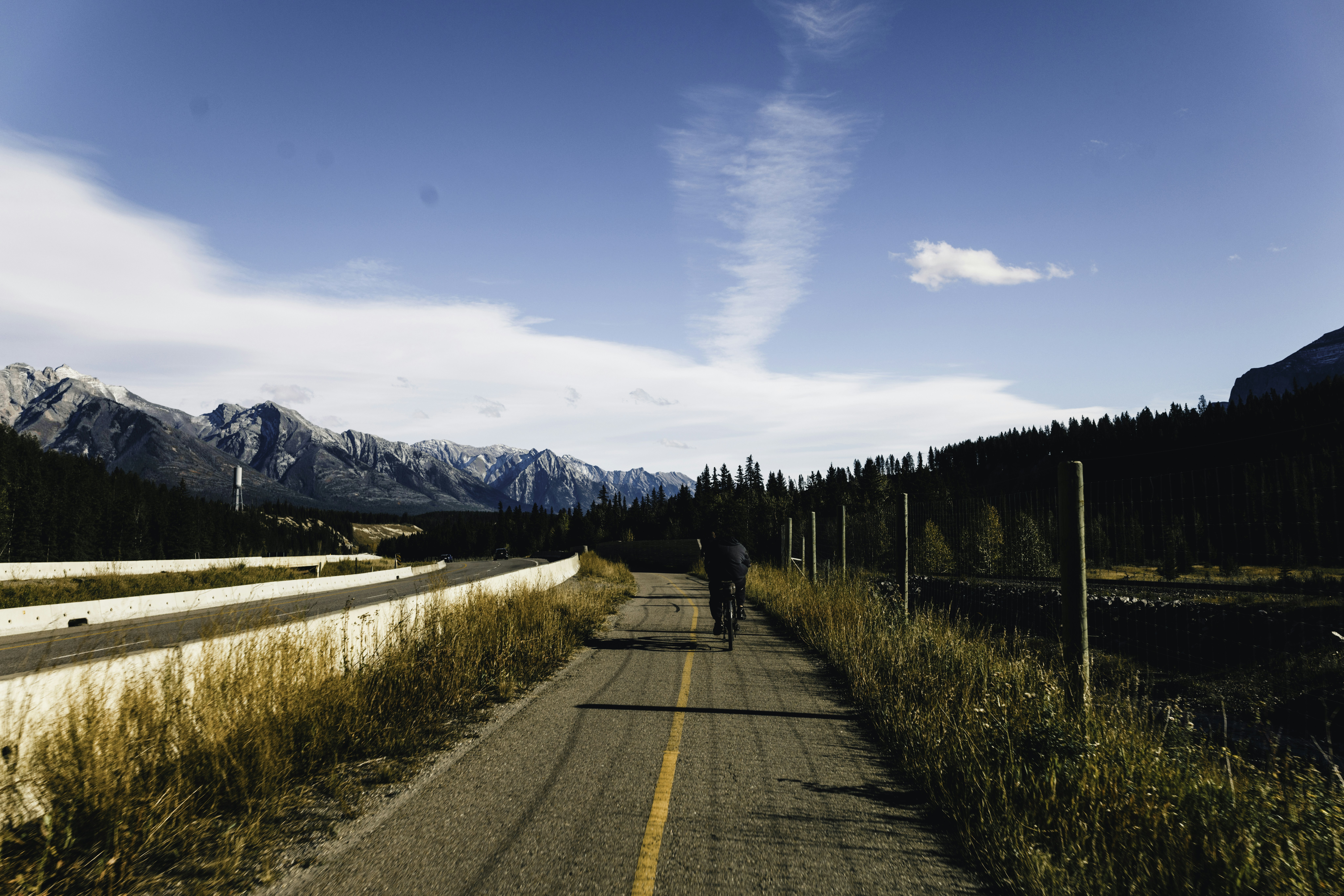 Two cyclists on a path with mountains in the background.