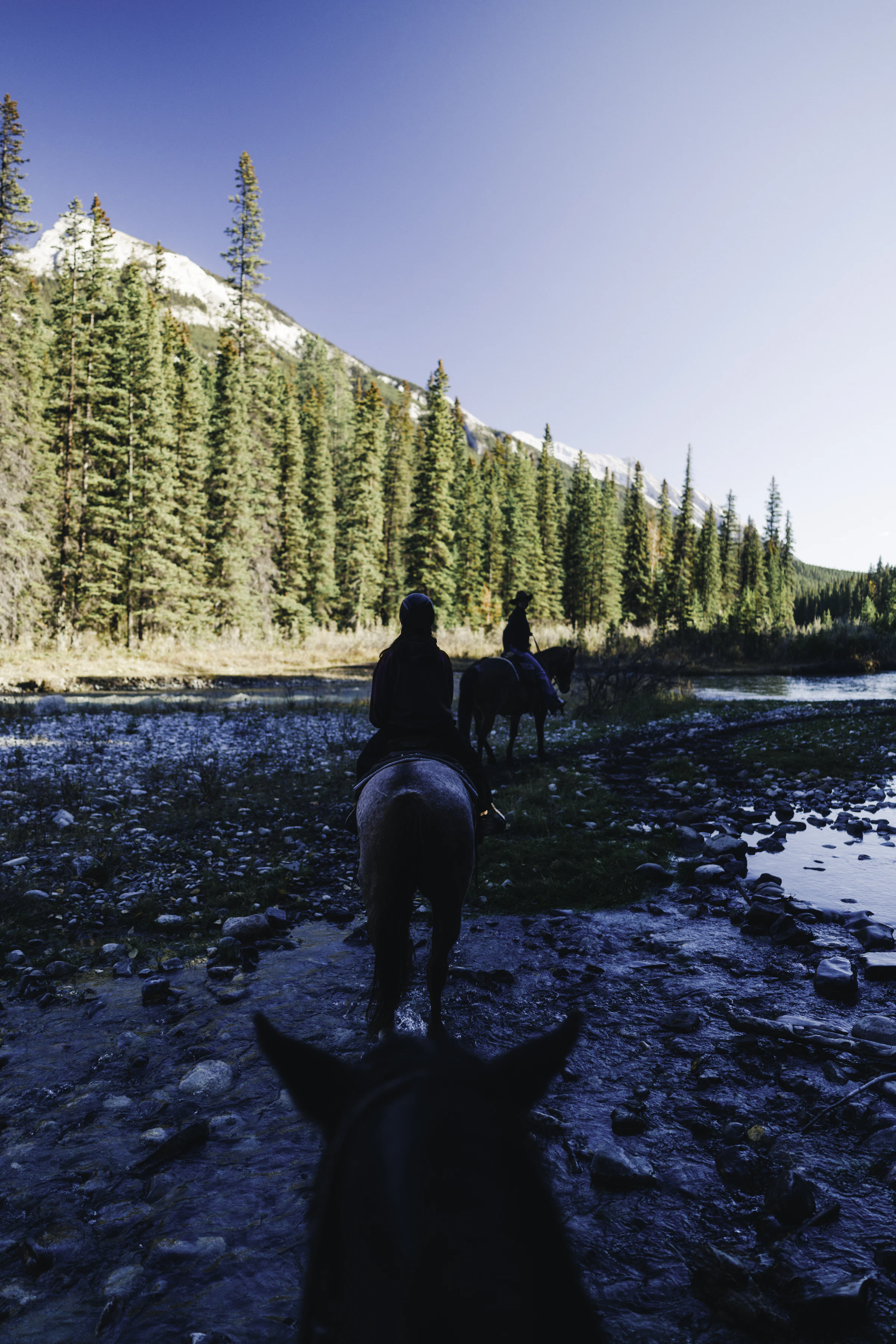 Two people horseback riding through mountain scenery