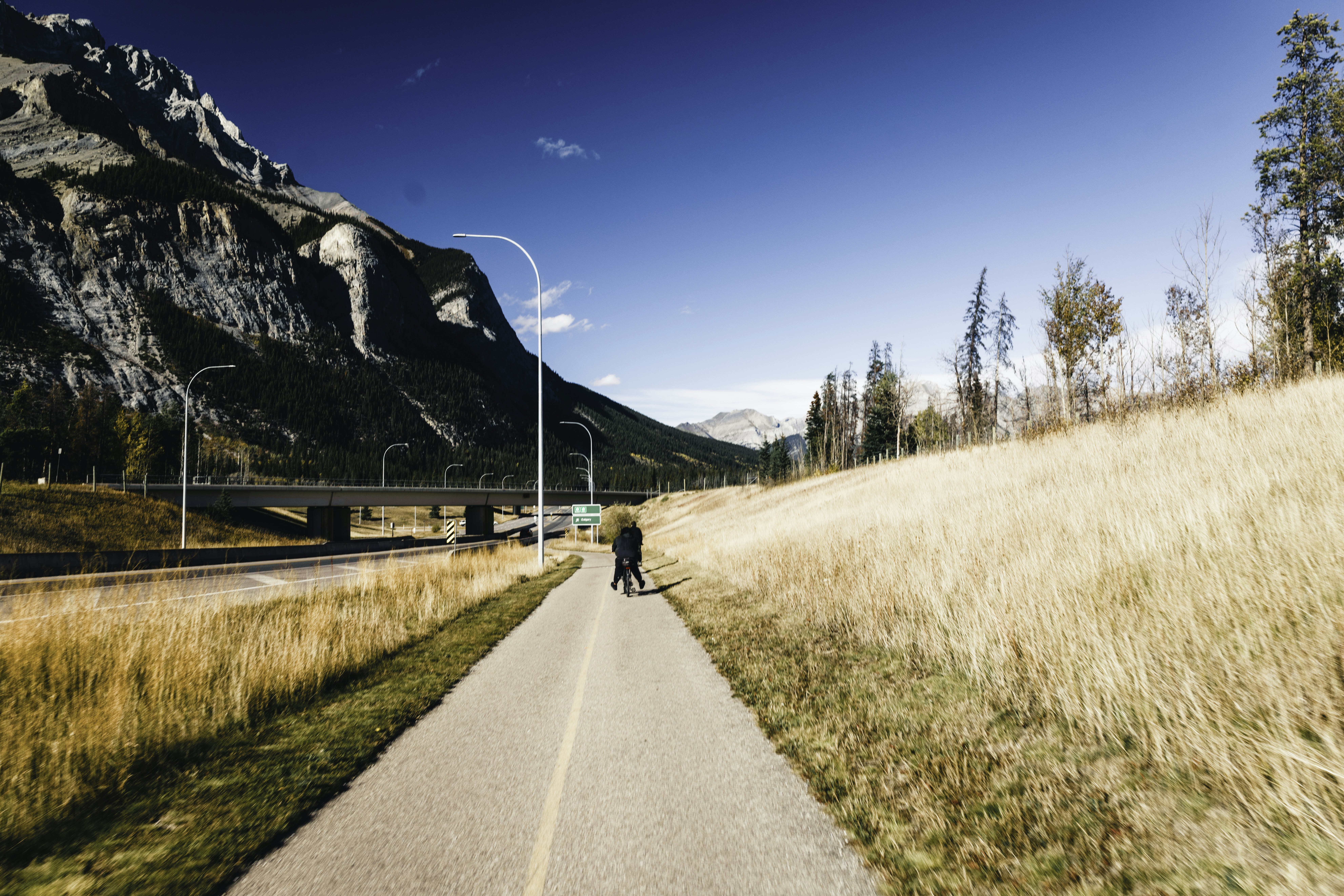 Person walking on a paved path beside a mountain