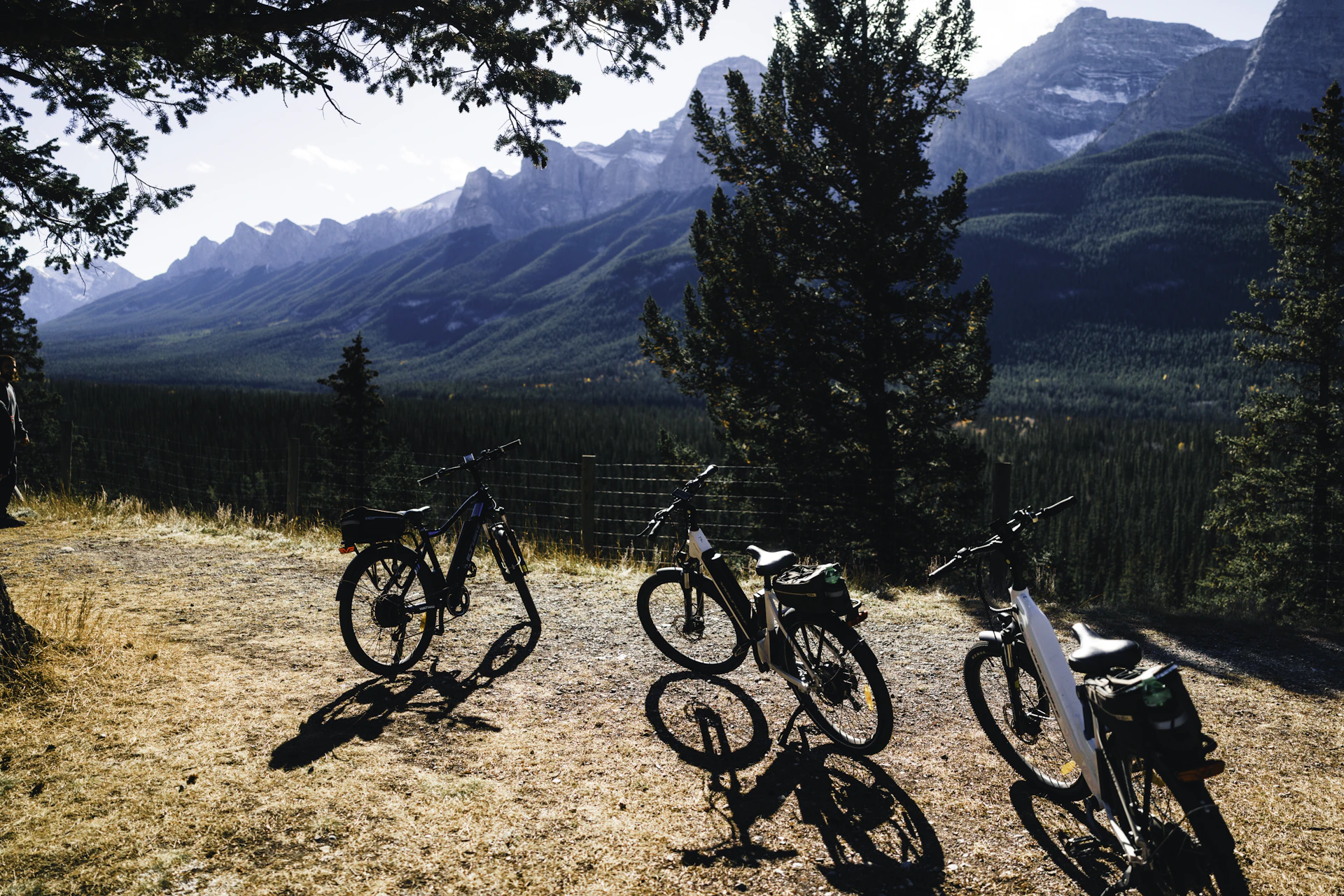 Four bicycles parked on a dirt path overlooking mountains.