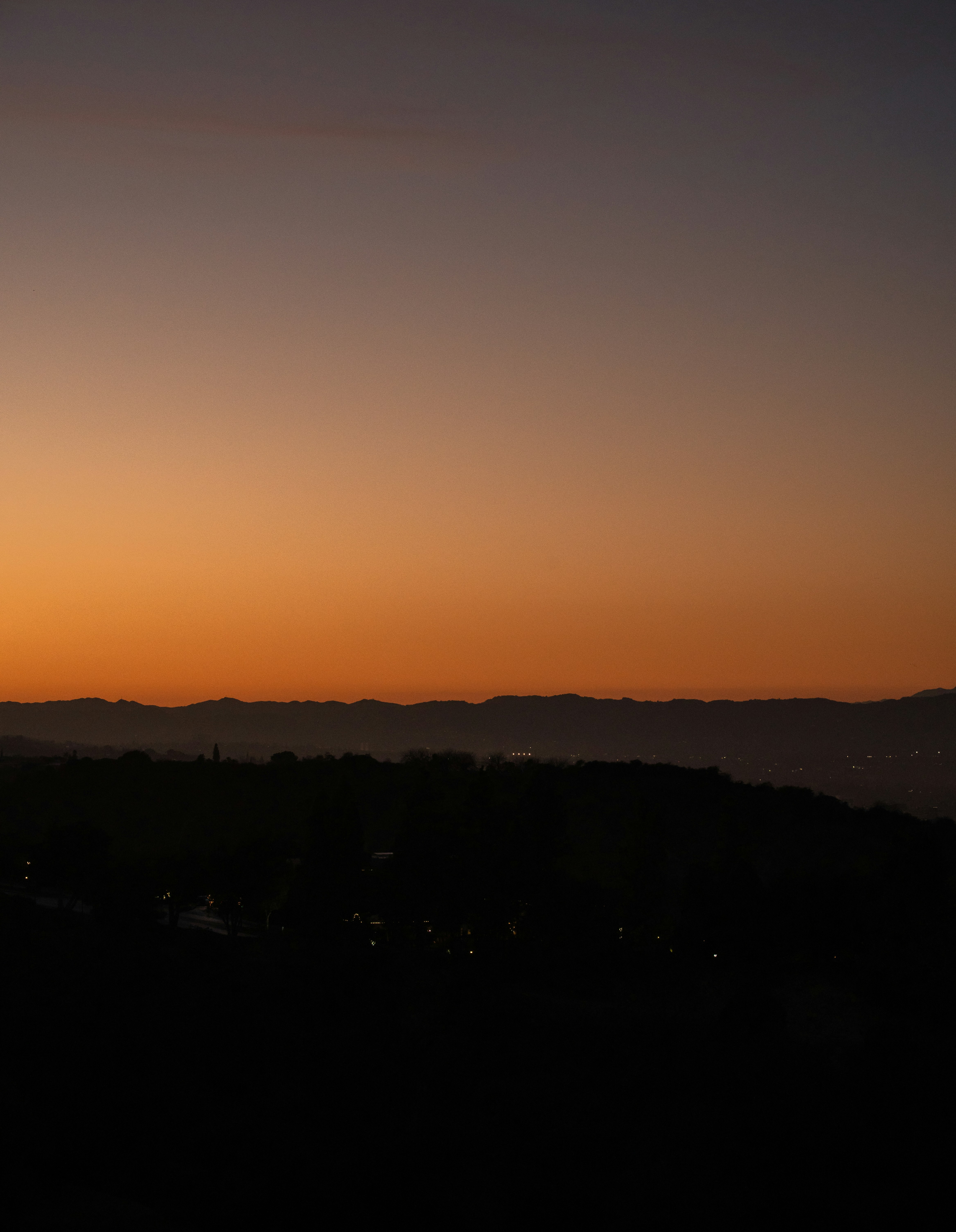 Sunset over a dark, silhouetted landscape.