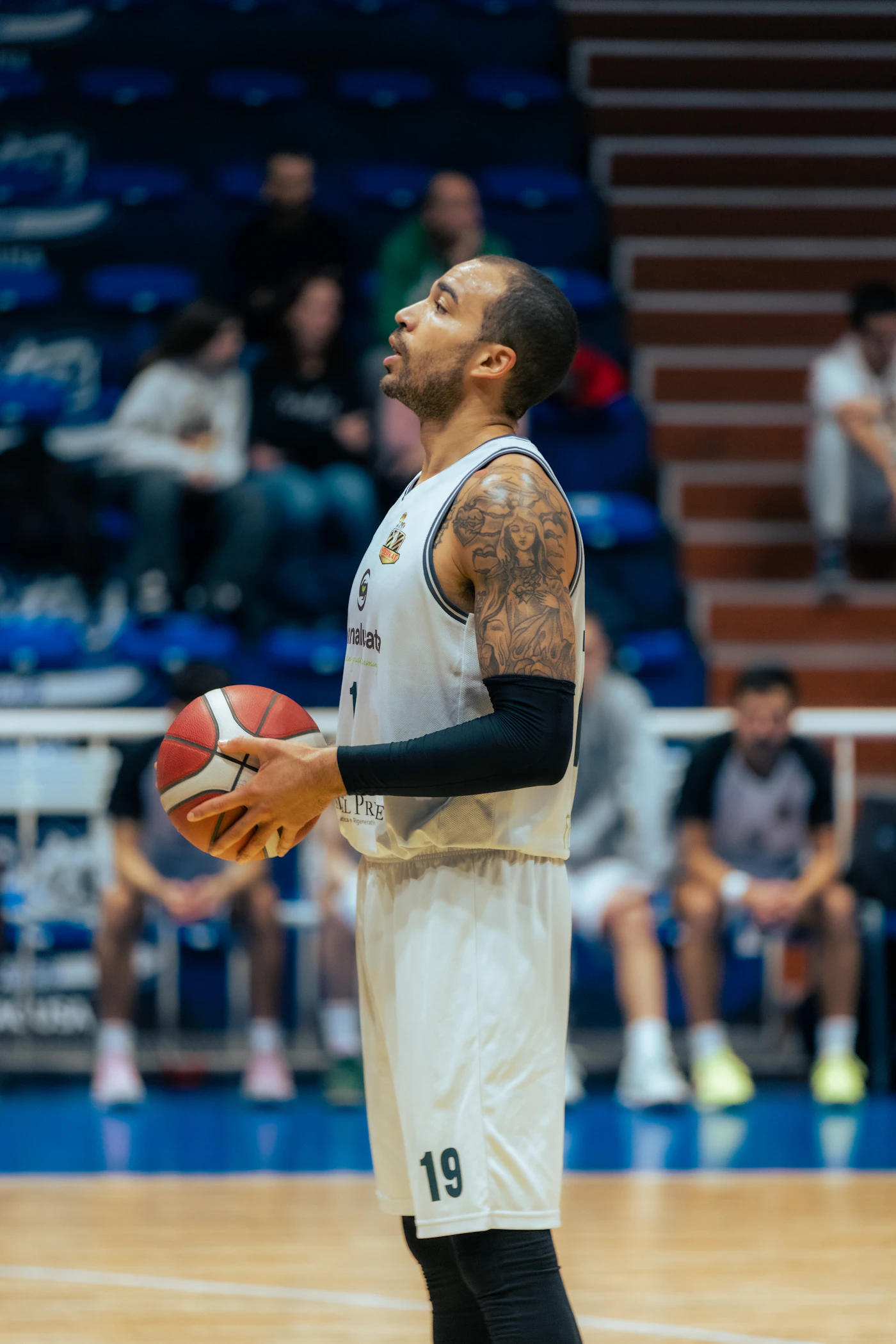 A basketball player holding a ball on an indoor court