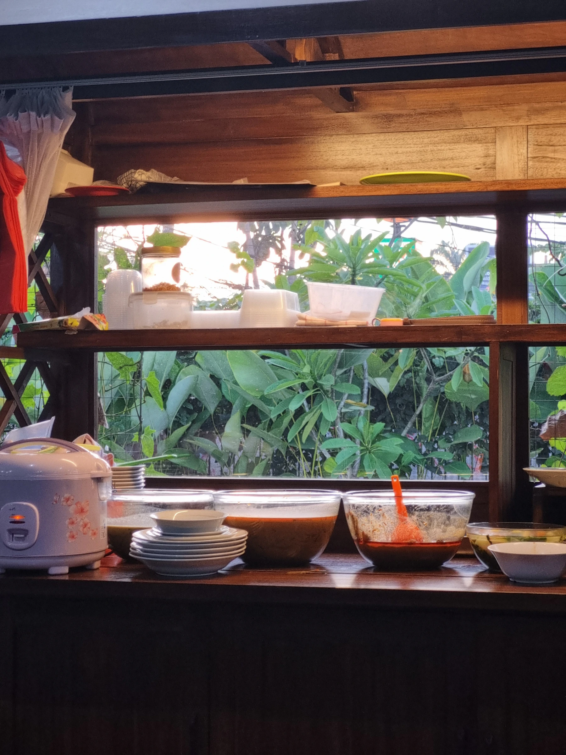 Rice cooker beside prepared dishes and serving bowls in a warm everyday kitchen setting