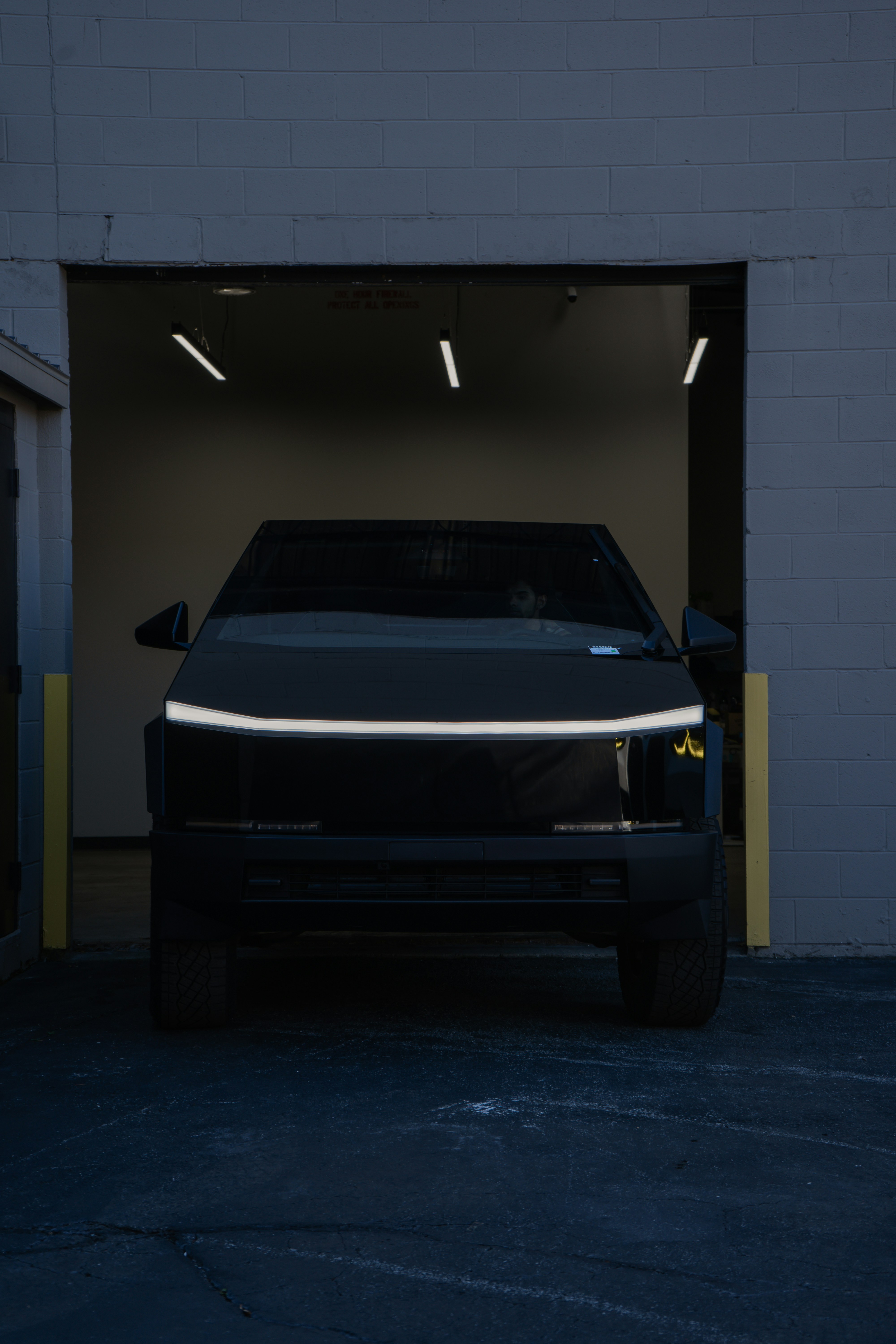 A black futuristic truck exiting a dark garage.