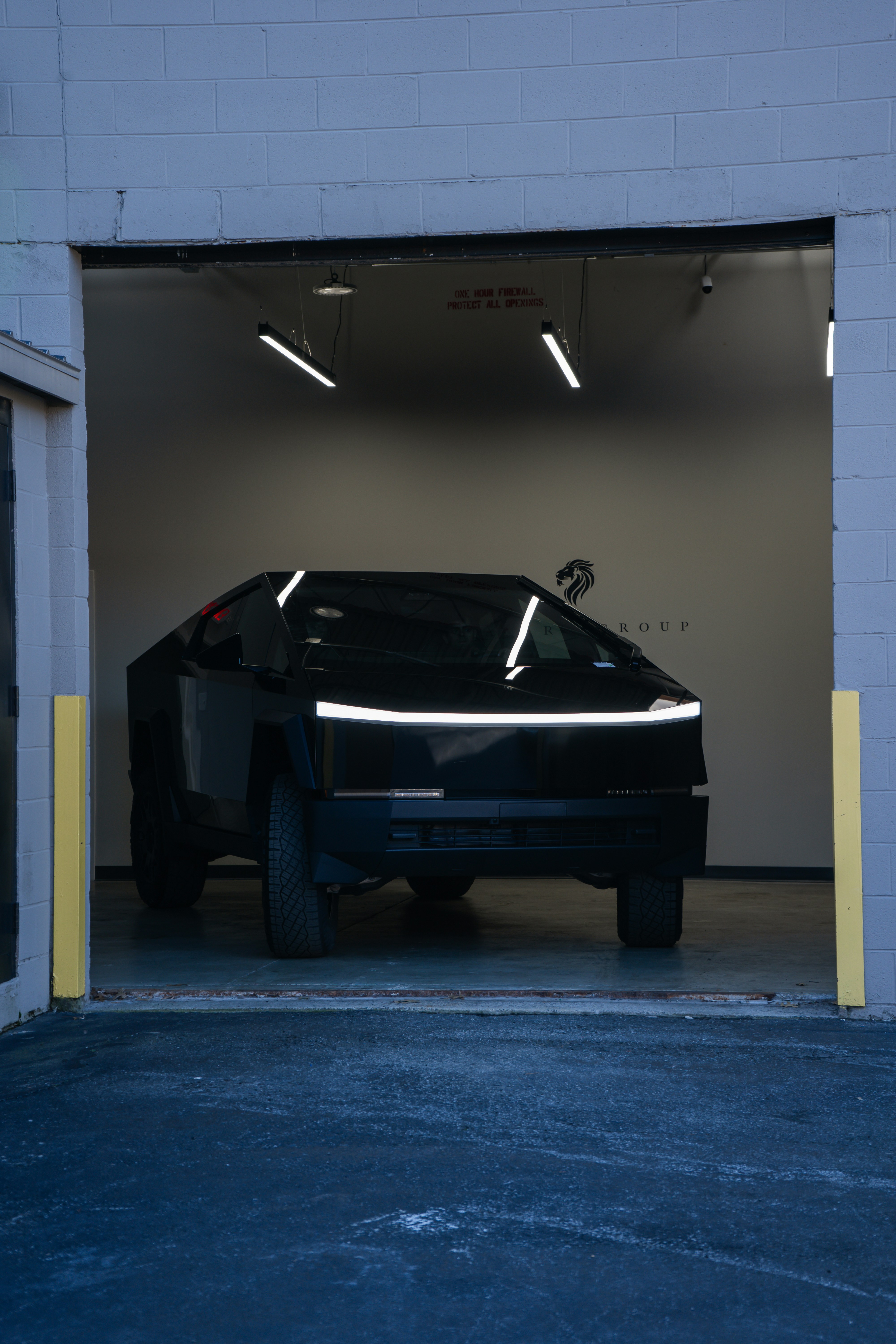 A black tesla cybertruck exiting a garage.