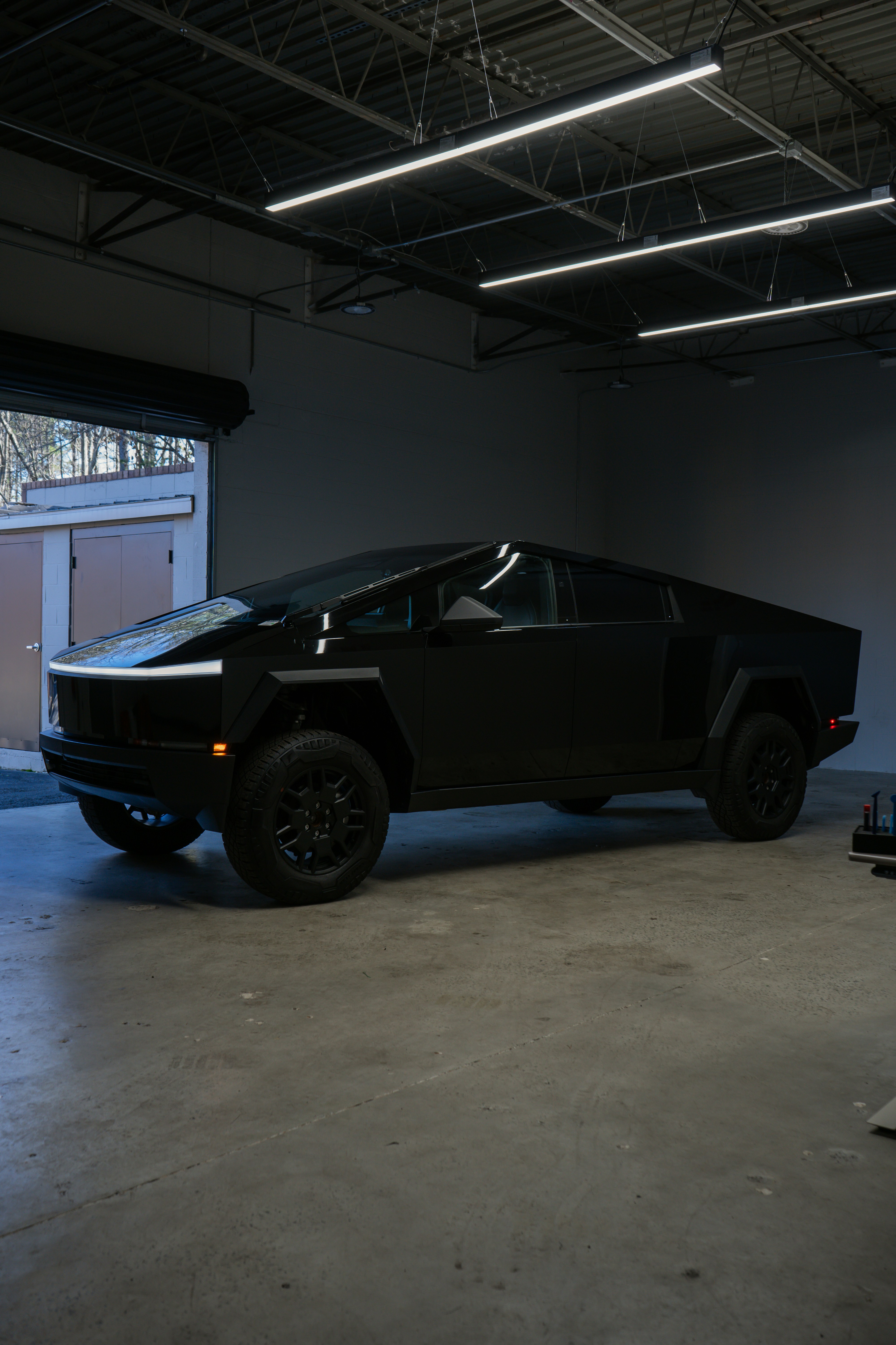A matte black futuristic truck parked indoors.