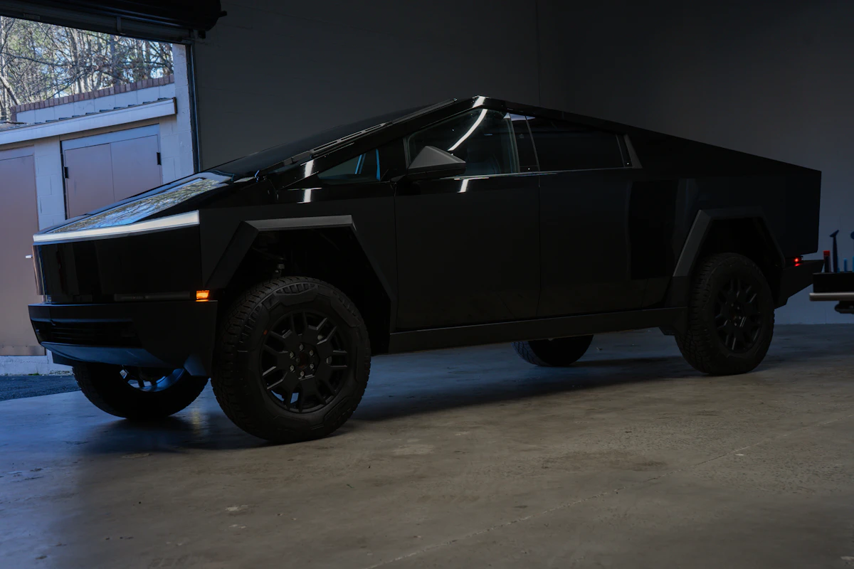Black matte Tesla Cybertruck parked indoors showcasing angular stainless steel design