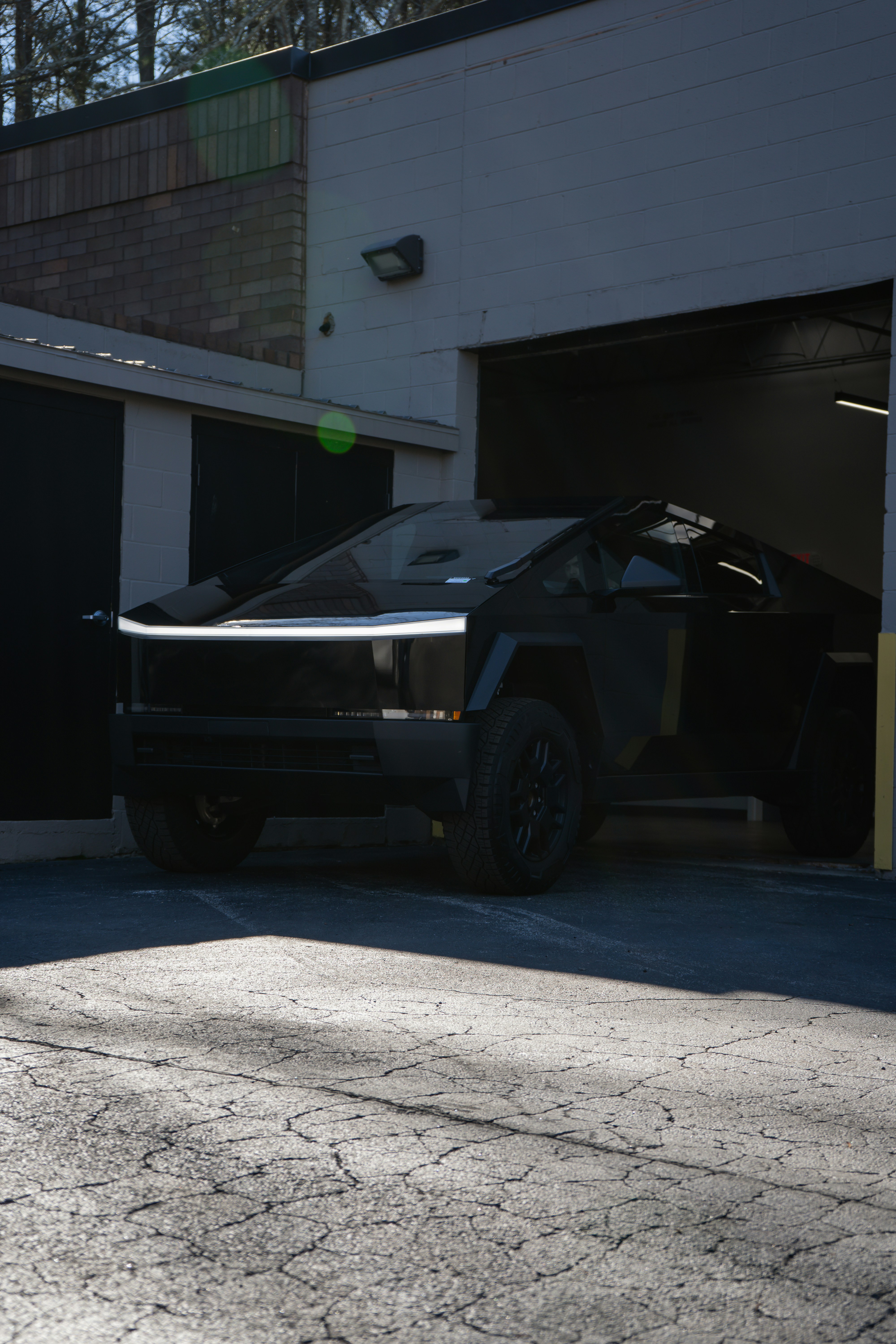 A black tesla cybertruck parked outside a garage.